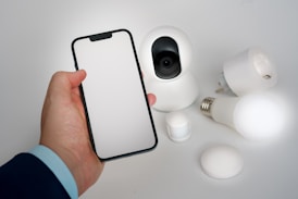 A person holding a smart phone next to a camera