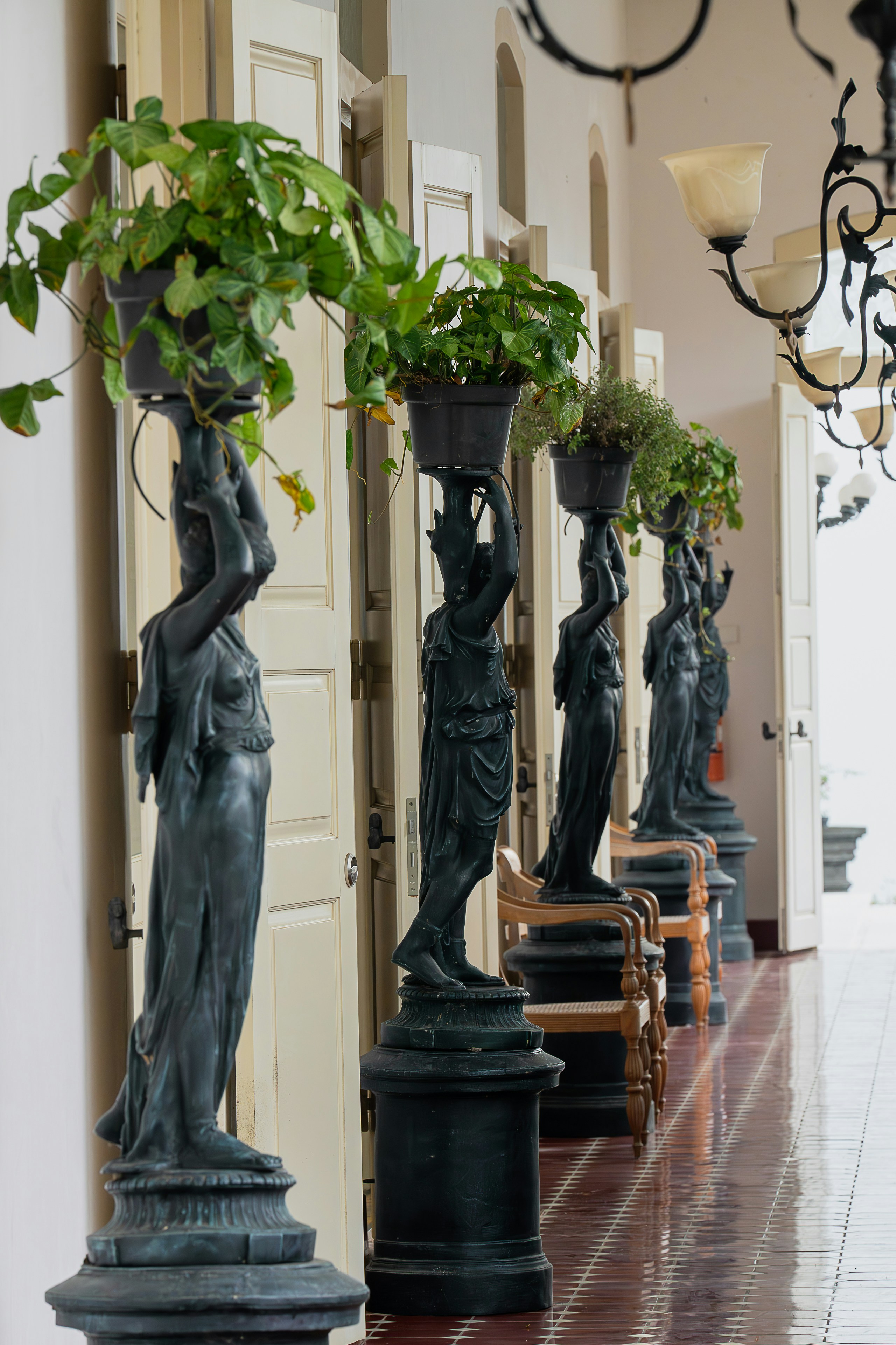 A hallway with statues and a chandelier hanging from the ceiling