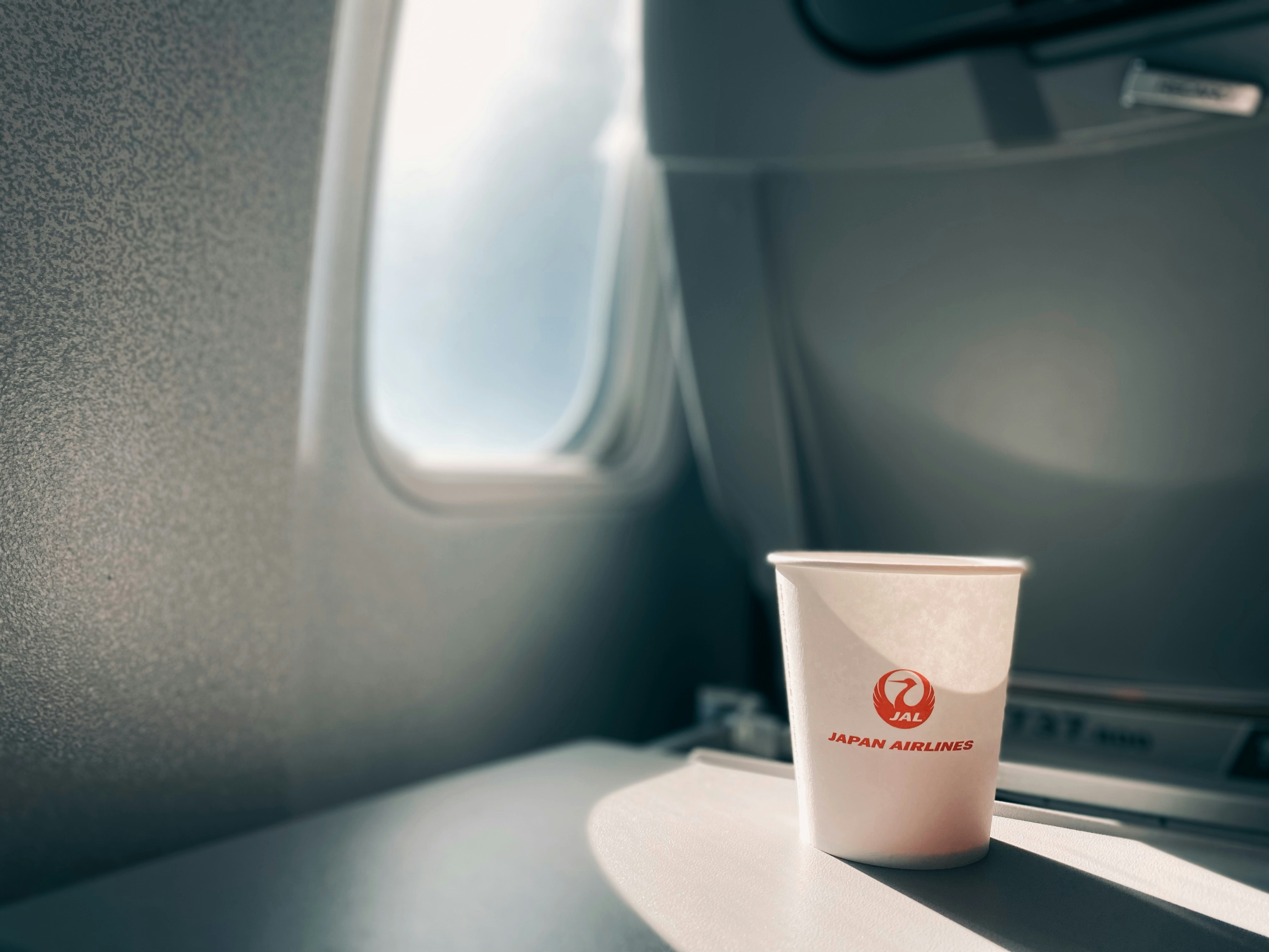 A cup of coffee sitting on an airplane seat Via Unsplash (by kurage)