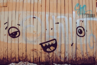 Graffiti on the side of a building with a face drawn on it