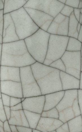 Cracked white ceramic surface with fine black lines.