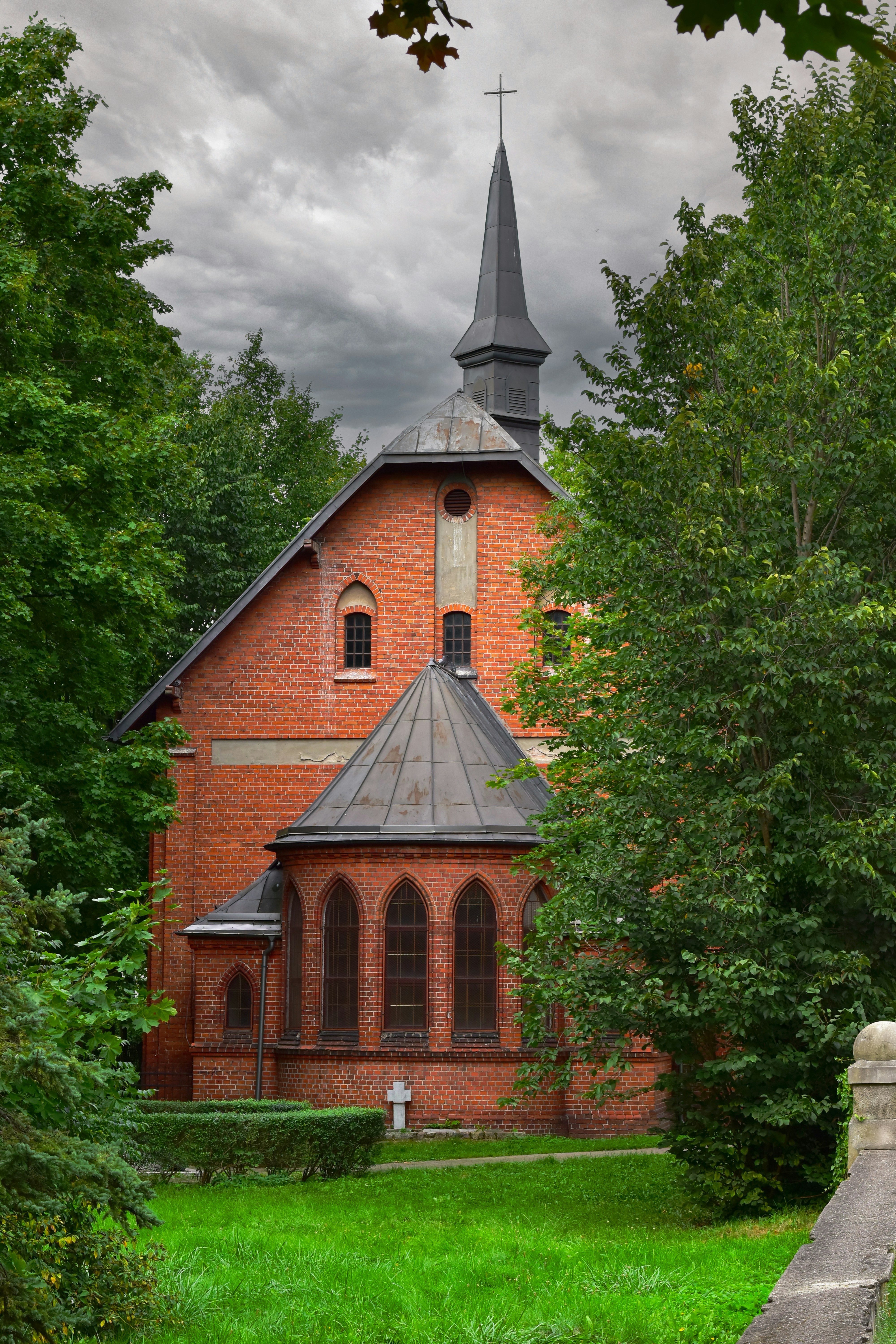 A red brick church with a steeple surrounded by trees