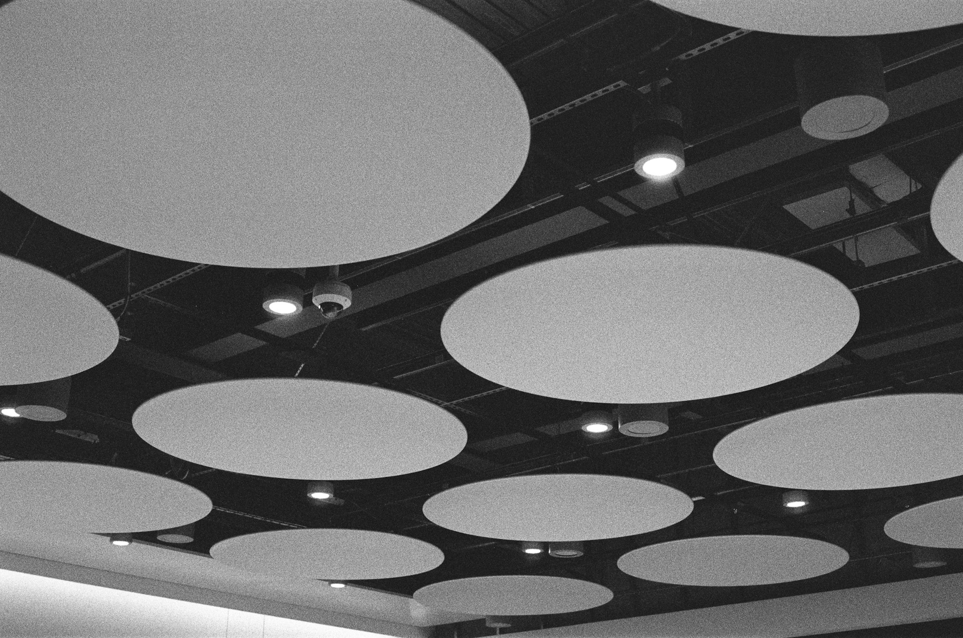 A black and white photo of a ceiling with circular lights