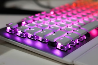 A close up of a computer keyboard with purple and red lights