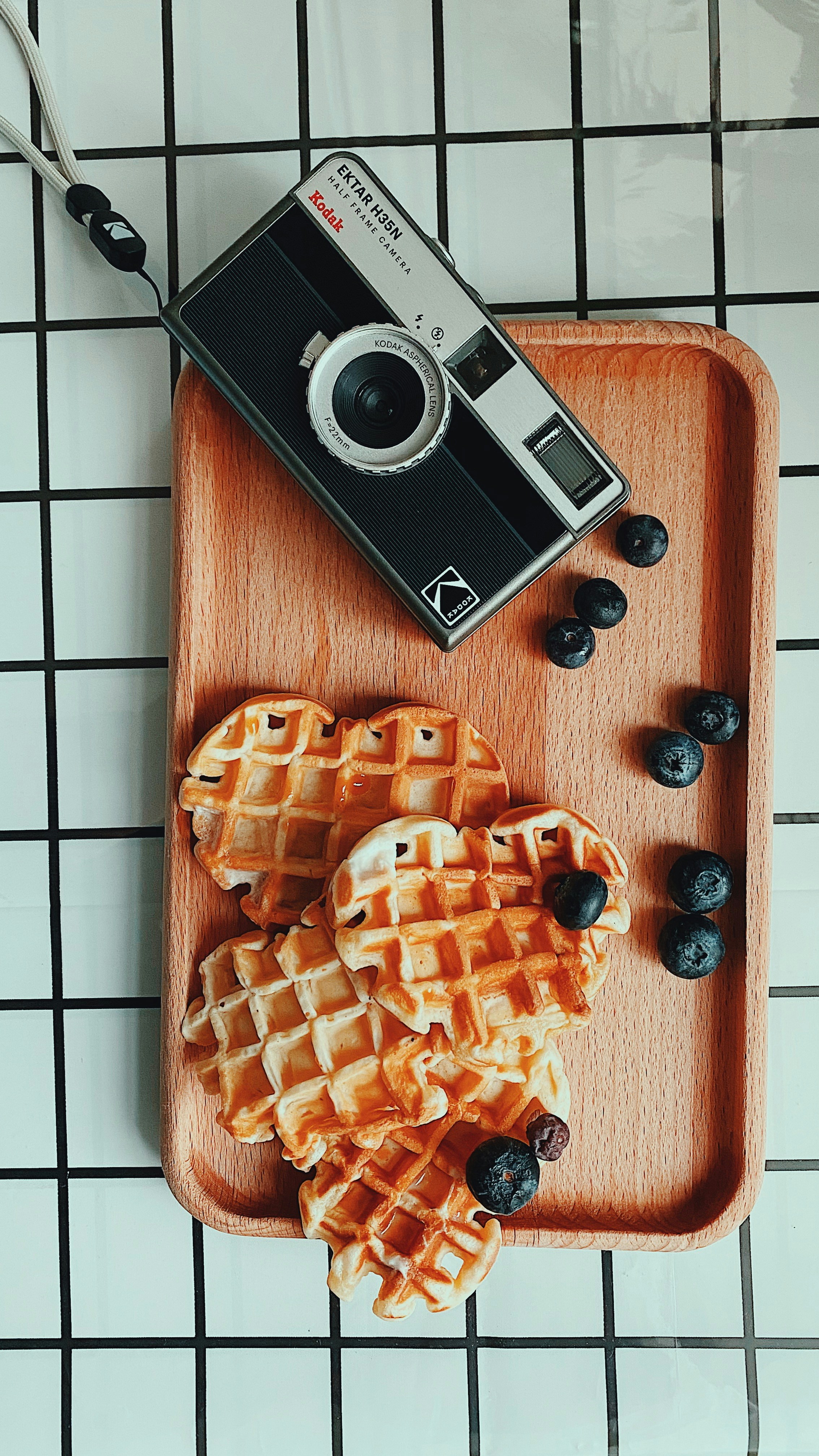 A wooden tray topped with waffles and blueberries