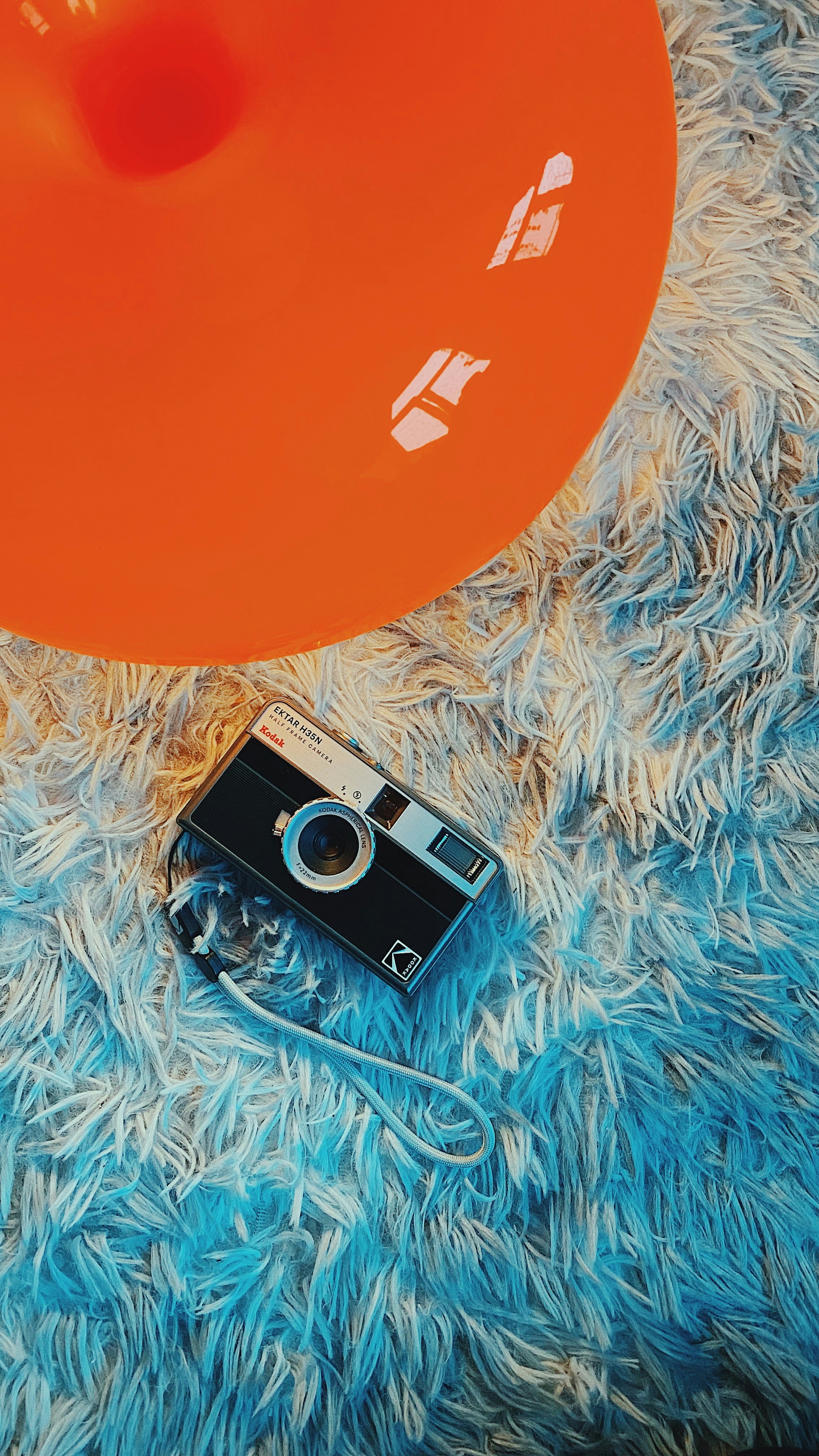 An orange ball and a camera on a blue carpet