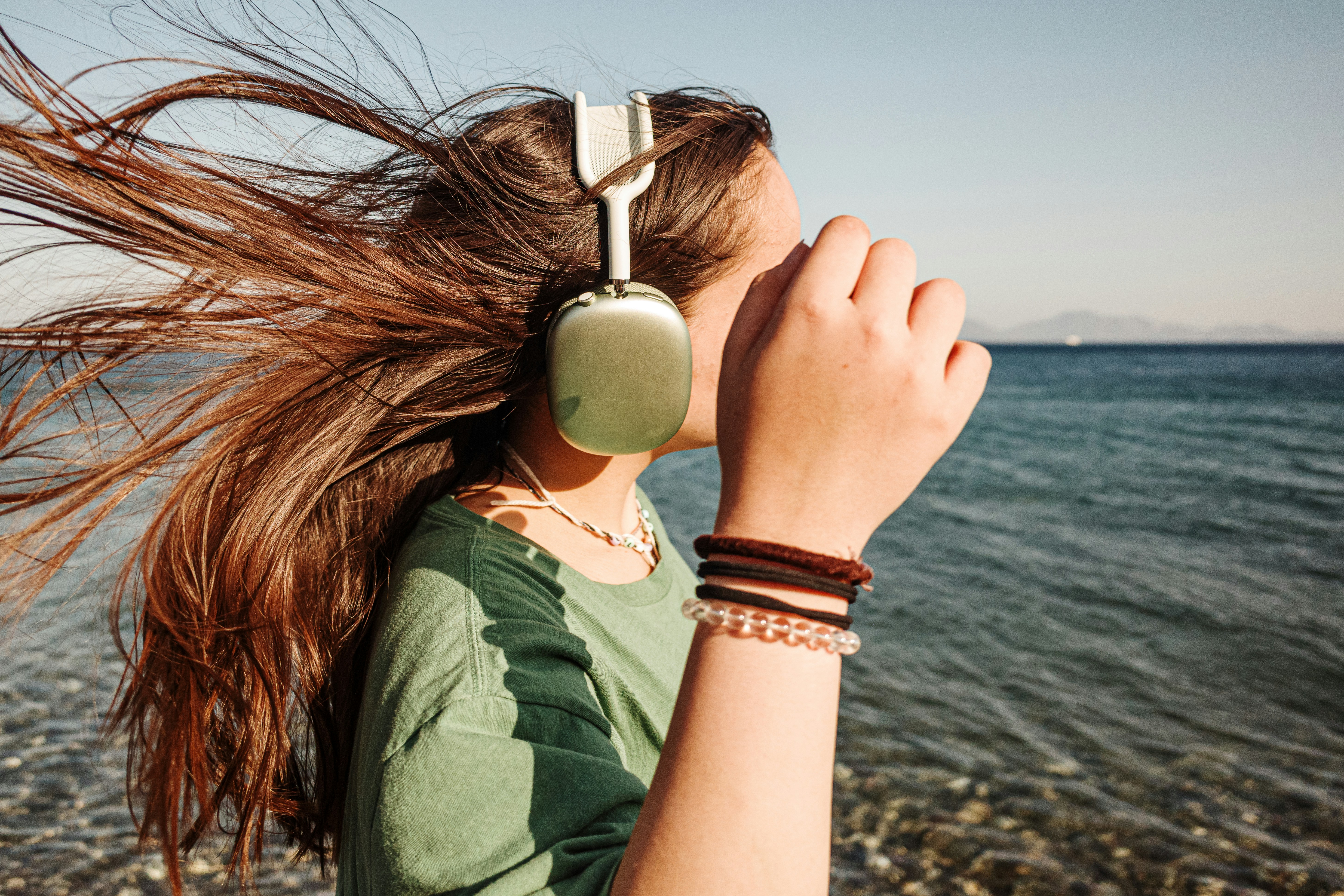 A woman with headphones standing on a beach