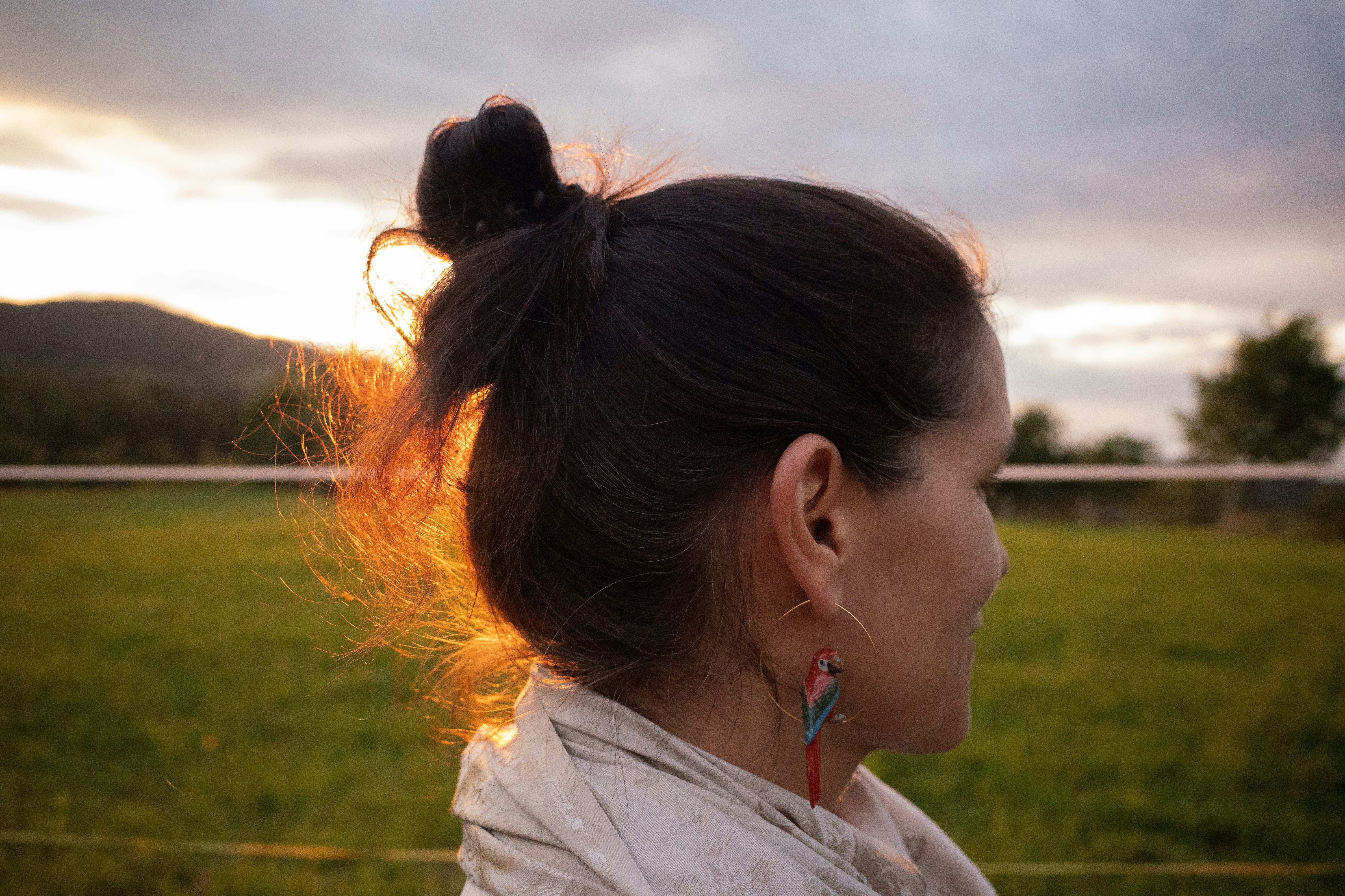 A woman standing in a field with her hair in a bun