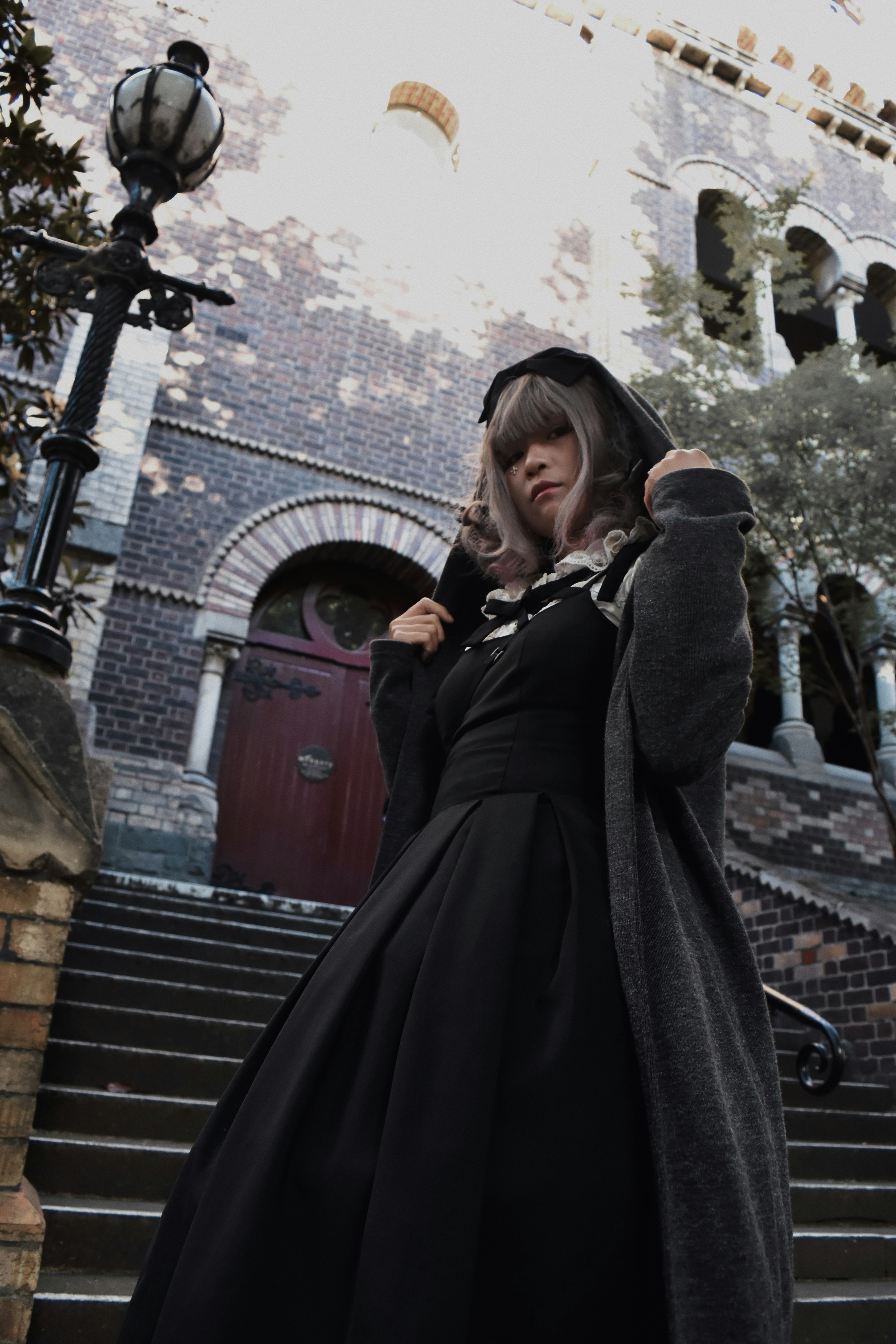 A woman in a long black dress is standing on a set of stairs