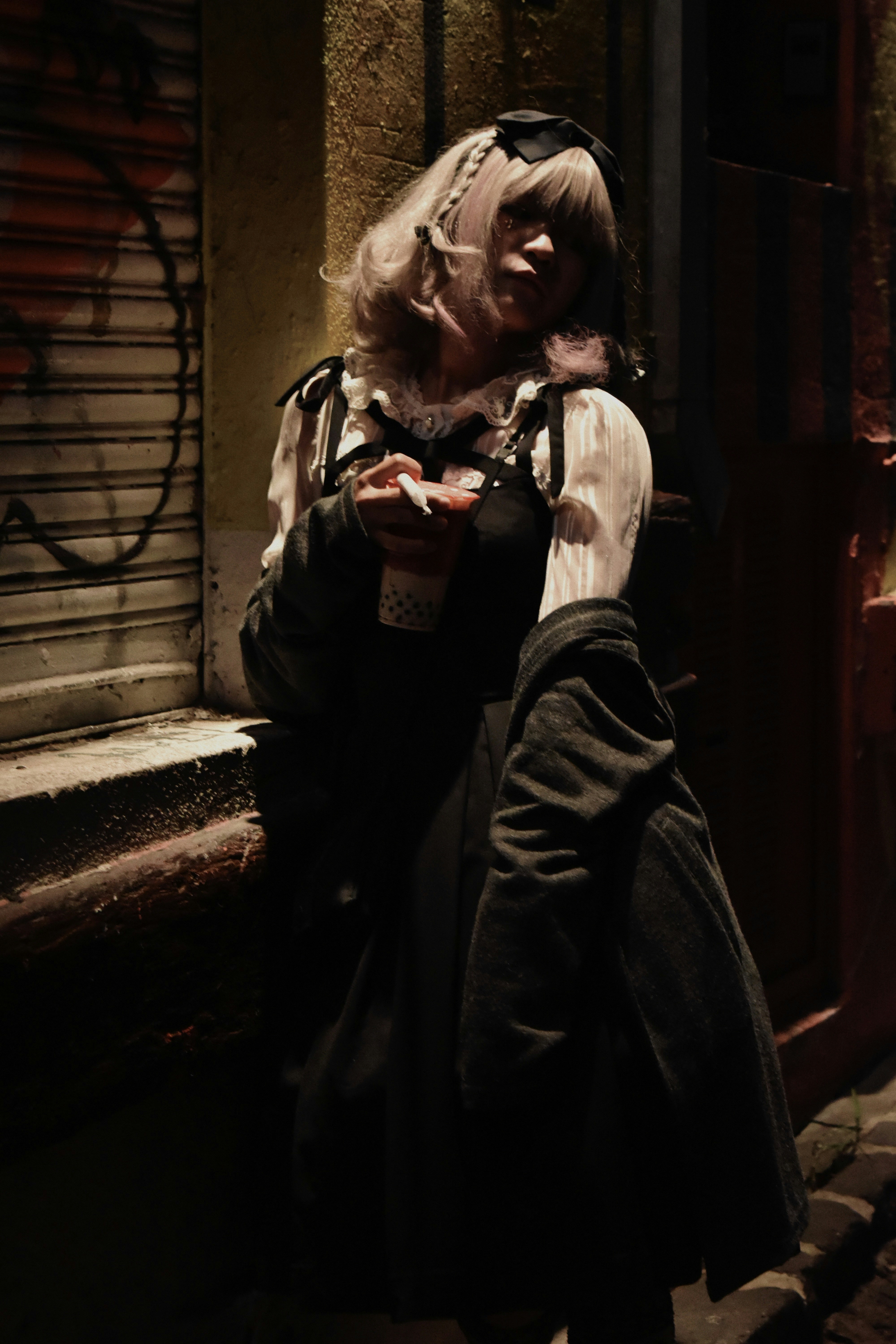 A woman standing on the side of a street next to a building