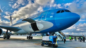 A blue and white airplane sitting on top of an airport tarmac