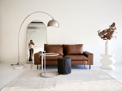 A living room with a brown couch and a white rug