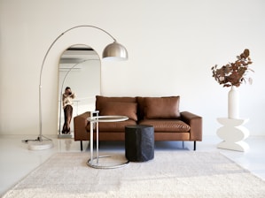 A living room with a brown couch and a white rug