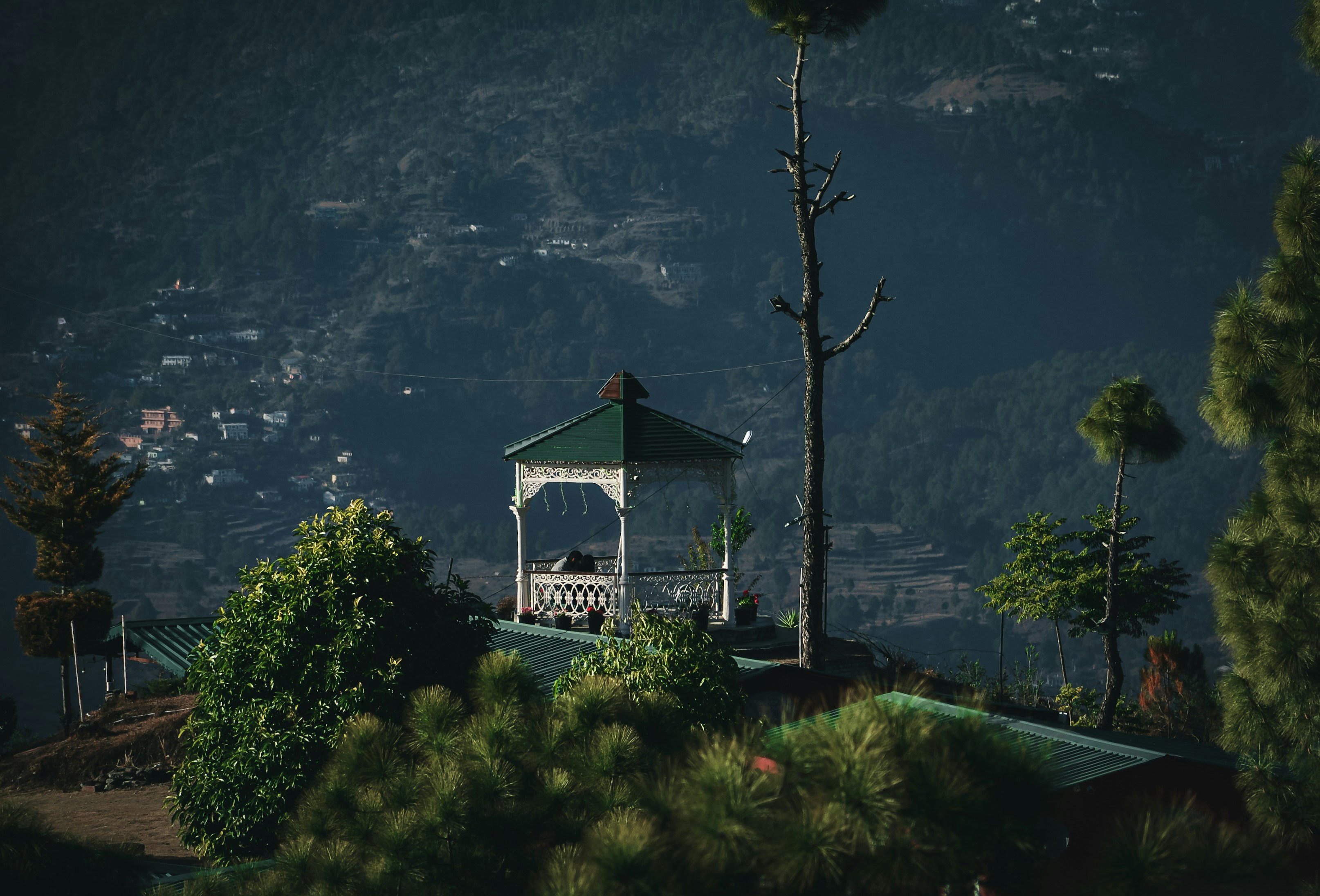 A white gazebo sitting on top of a lush green hillside