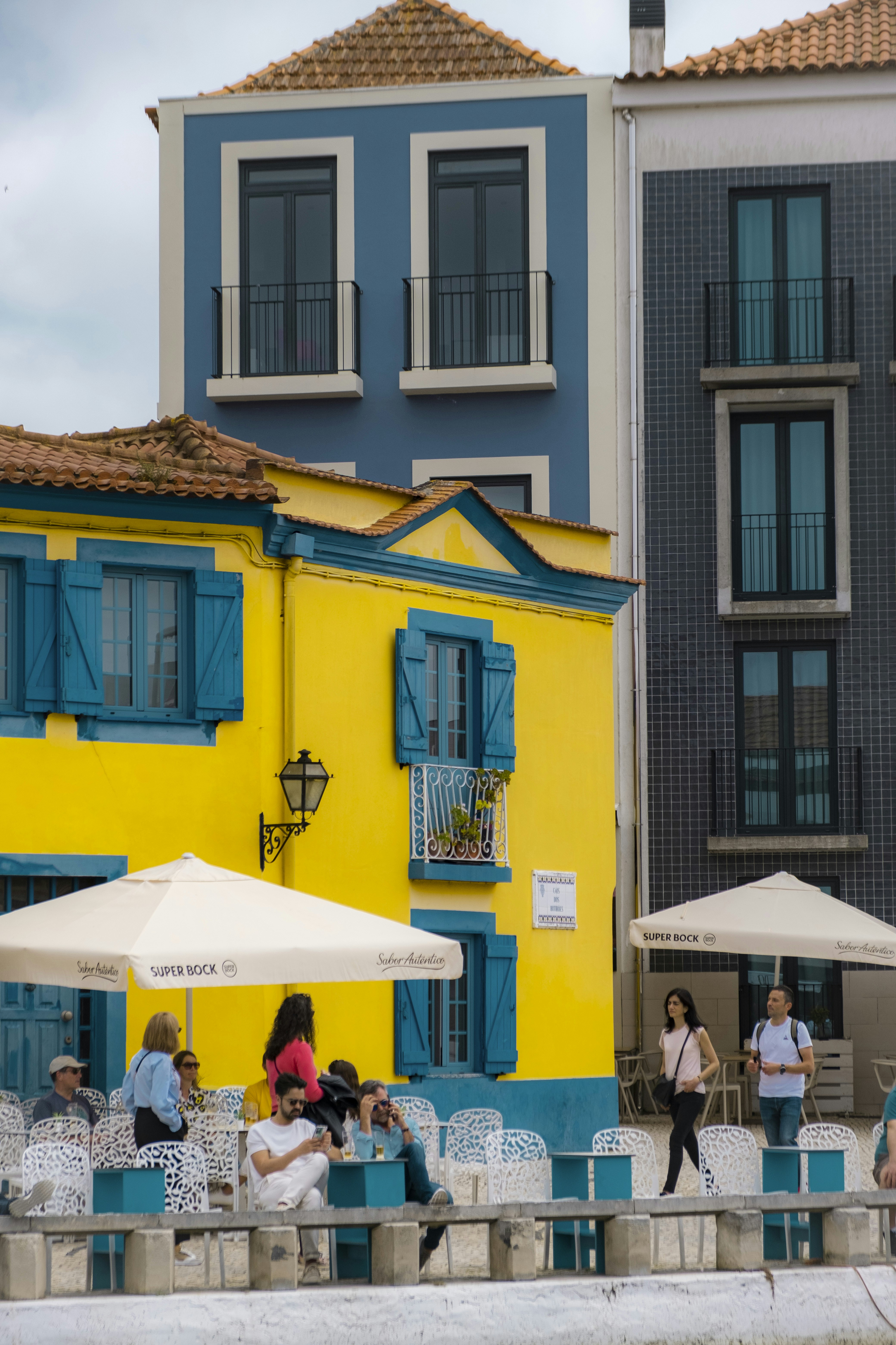 A group of people sitting outside of a yellow and blue building