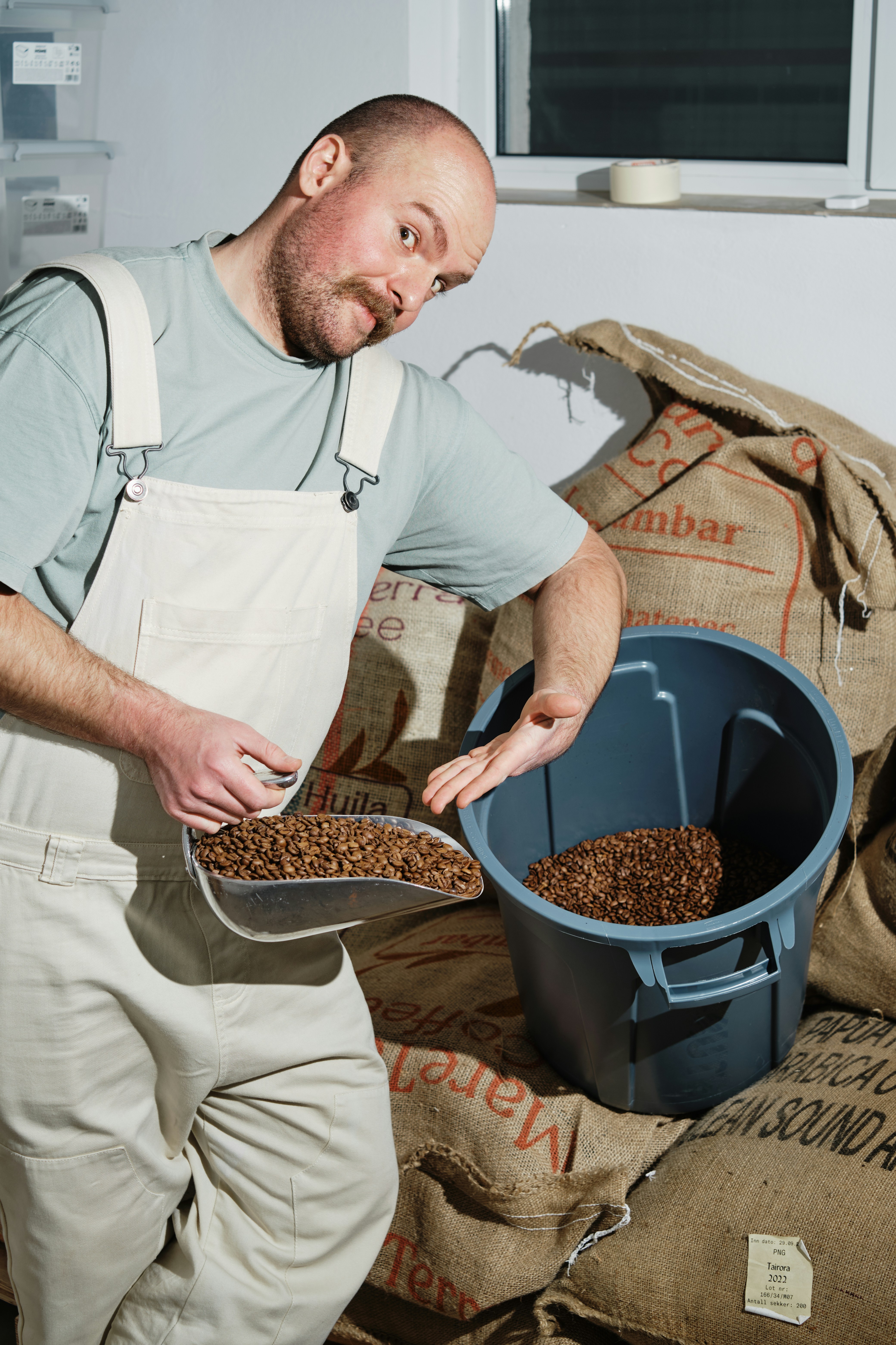 A man in an apron scooping grain out of a bucket