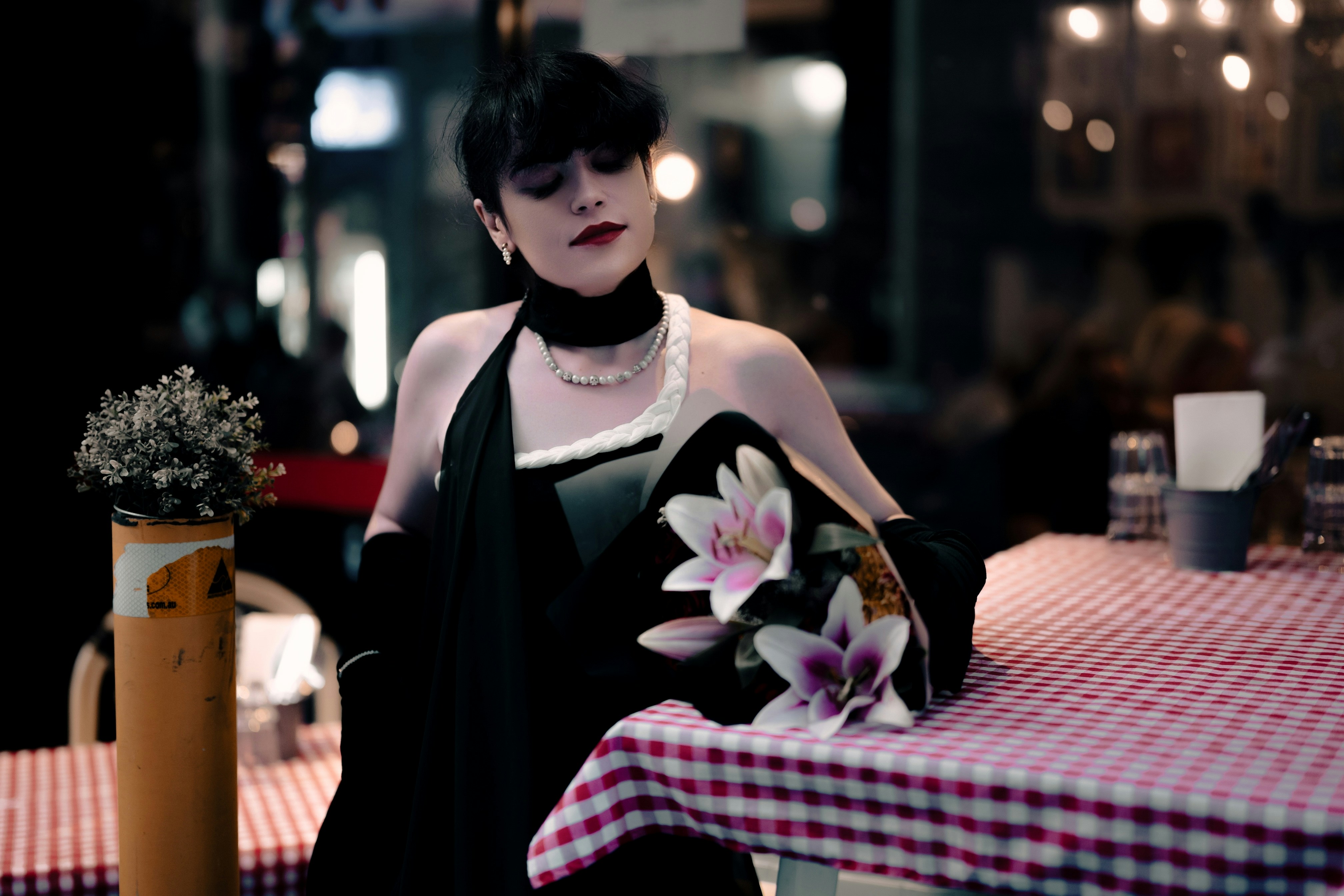 A woman in a black dress standing at a table