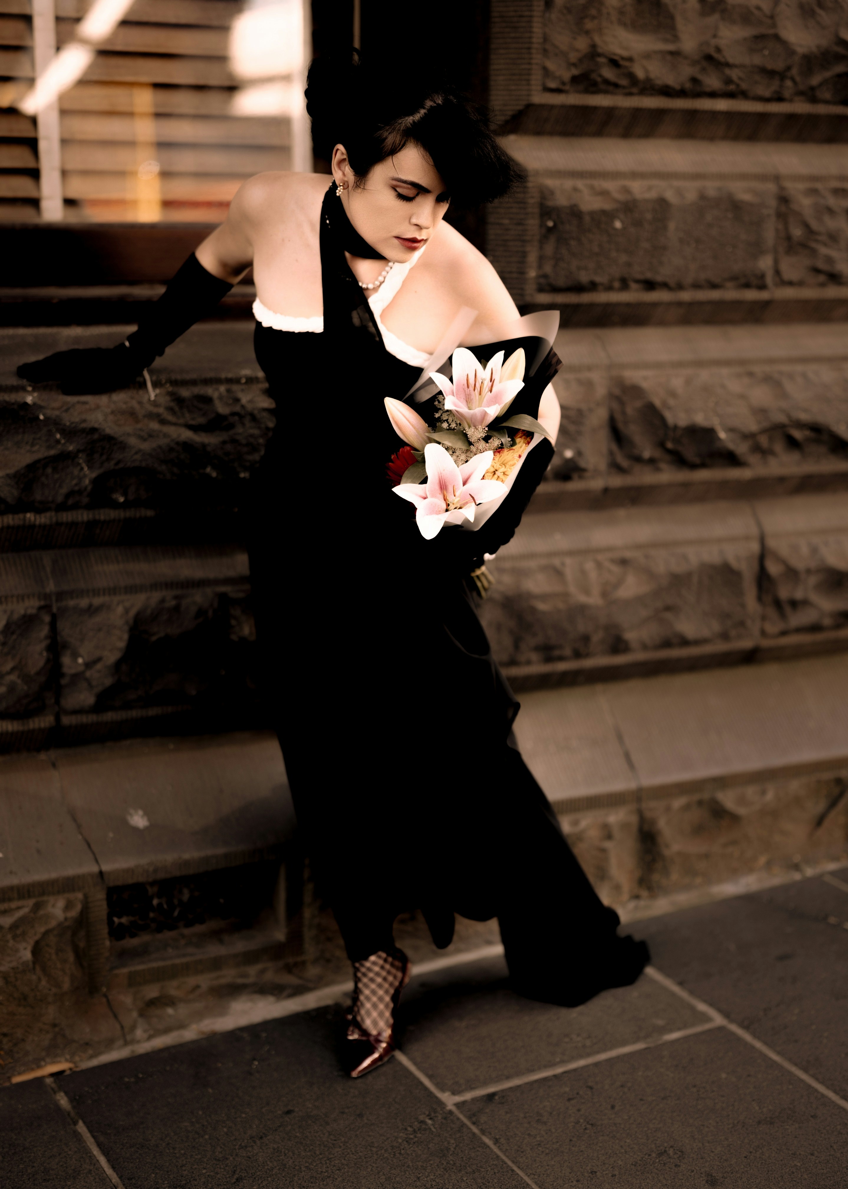 A woman in a black dress standing on steps