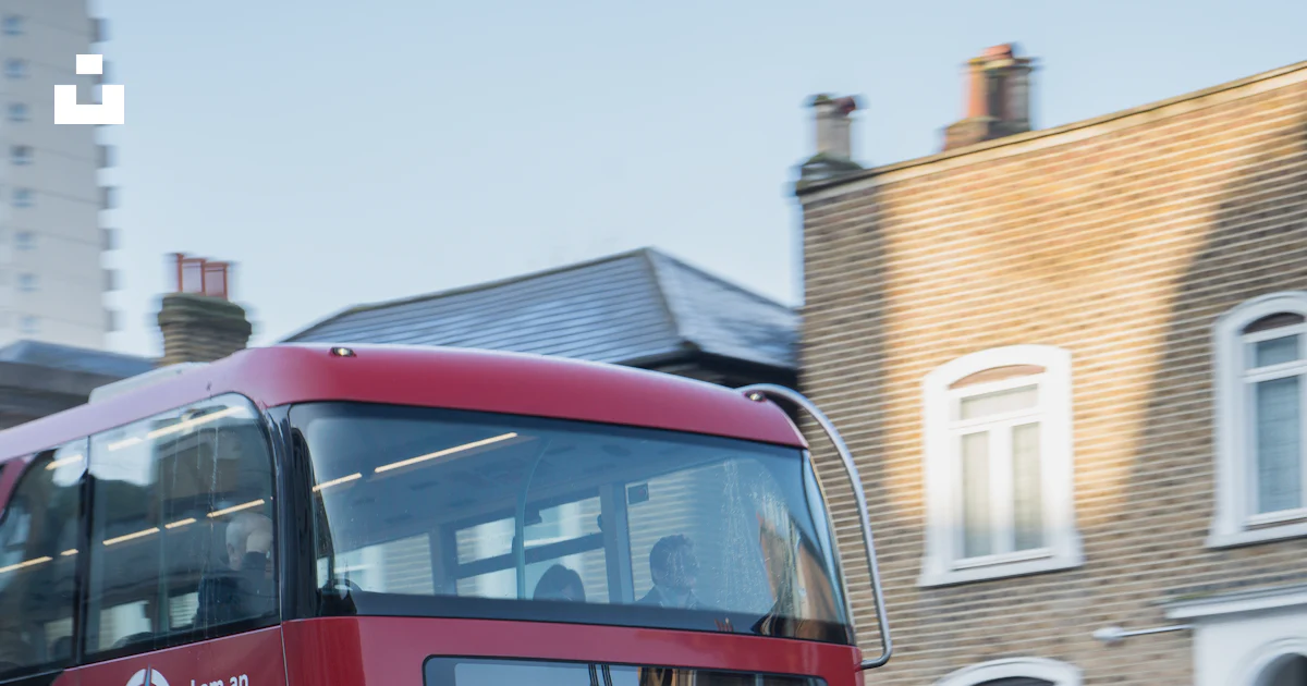 A red double decker bus driving down a street photo – Free London Image ...
