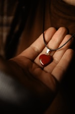 A person holding a red stone in their hand