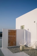 A white house with a wooden door and a white chair