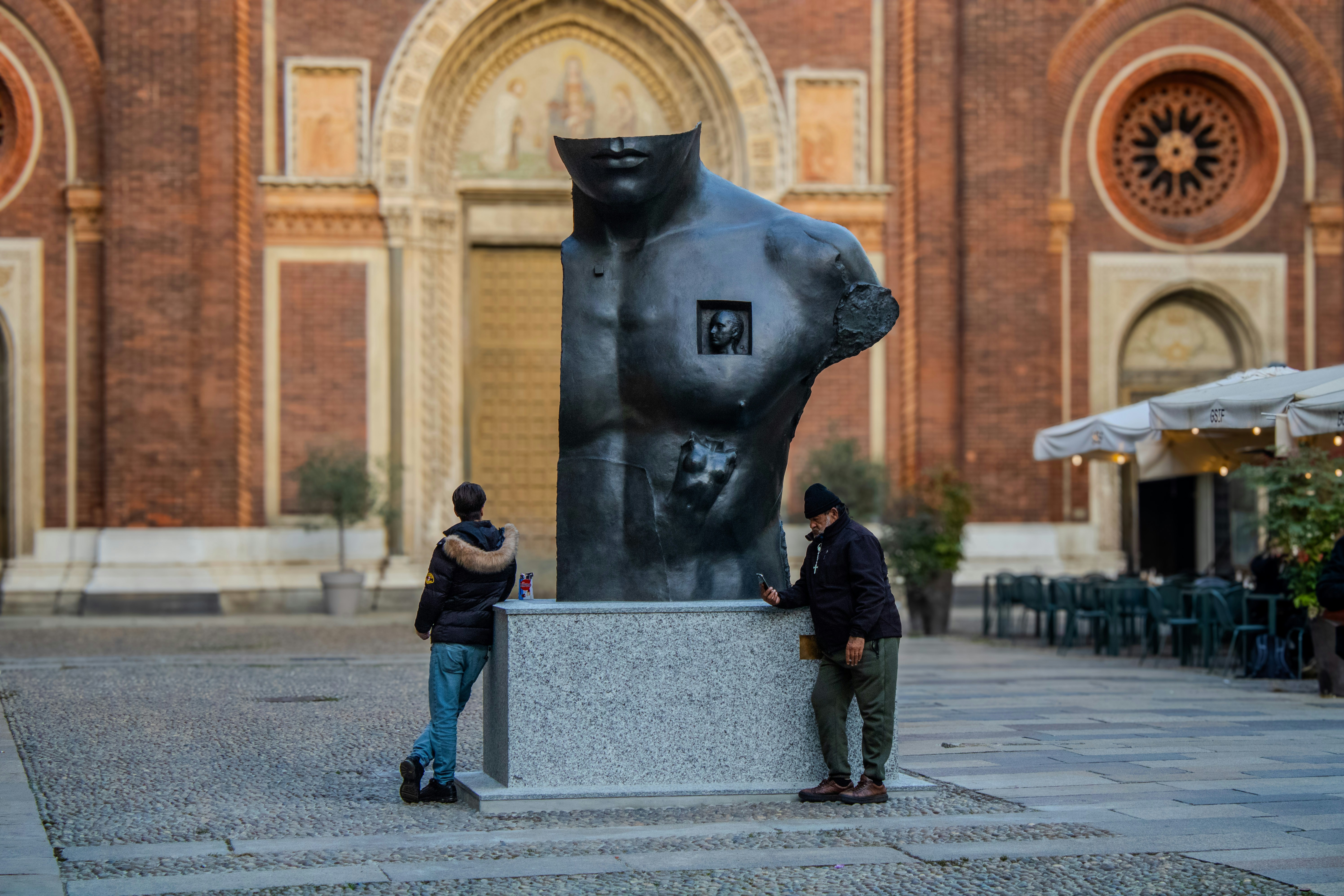 A couple of people standing next to a statue