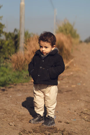 A little boy standing on a dirt road