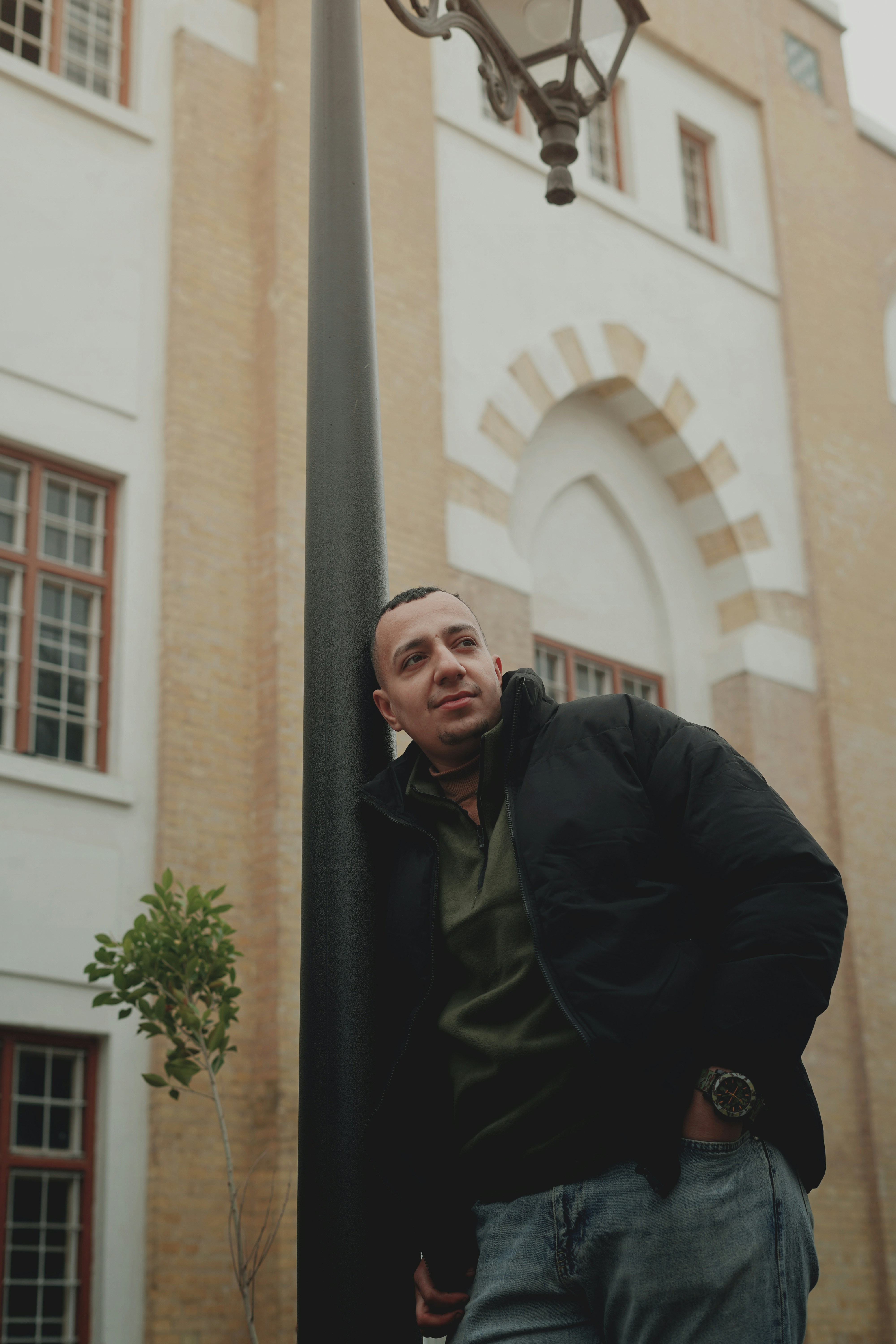 A man leaning against a lamp post in front of a building