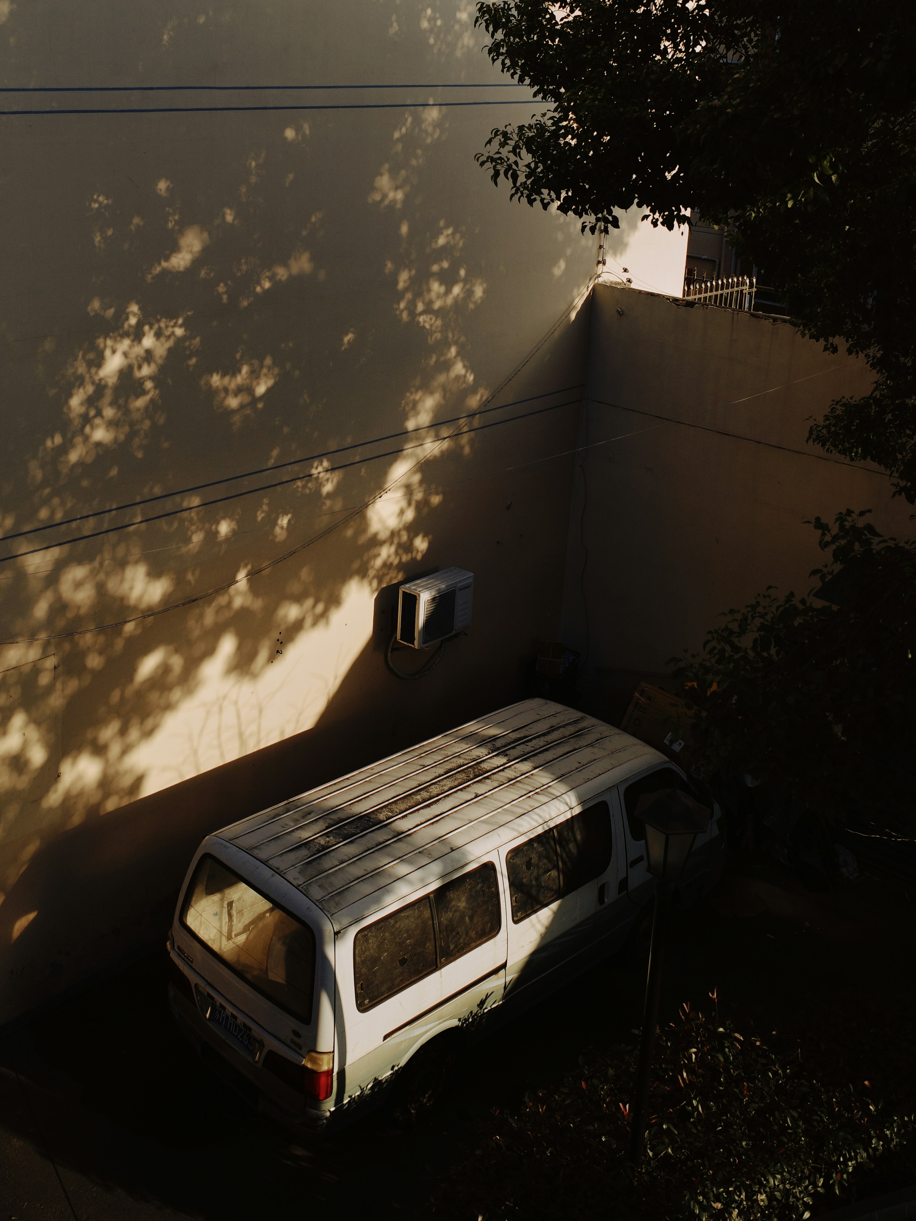 A white van parked next to a tree