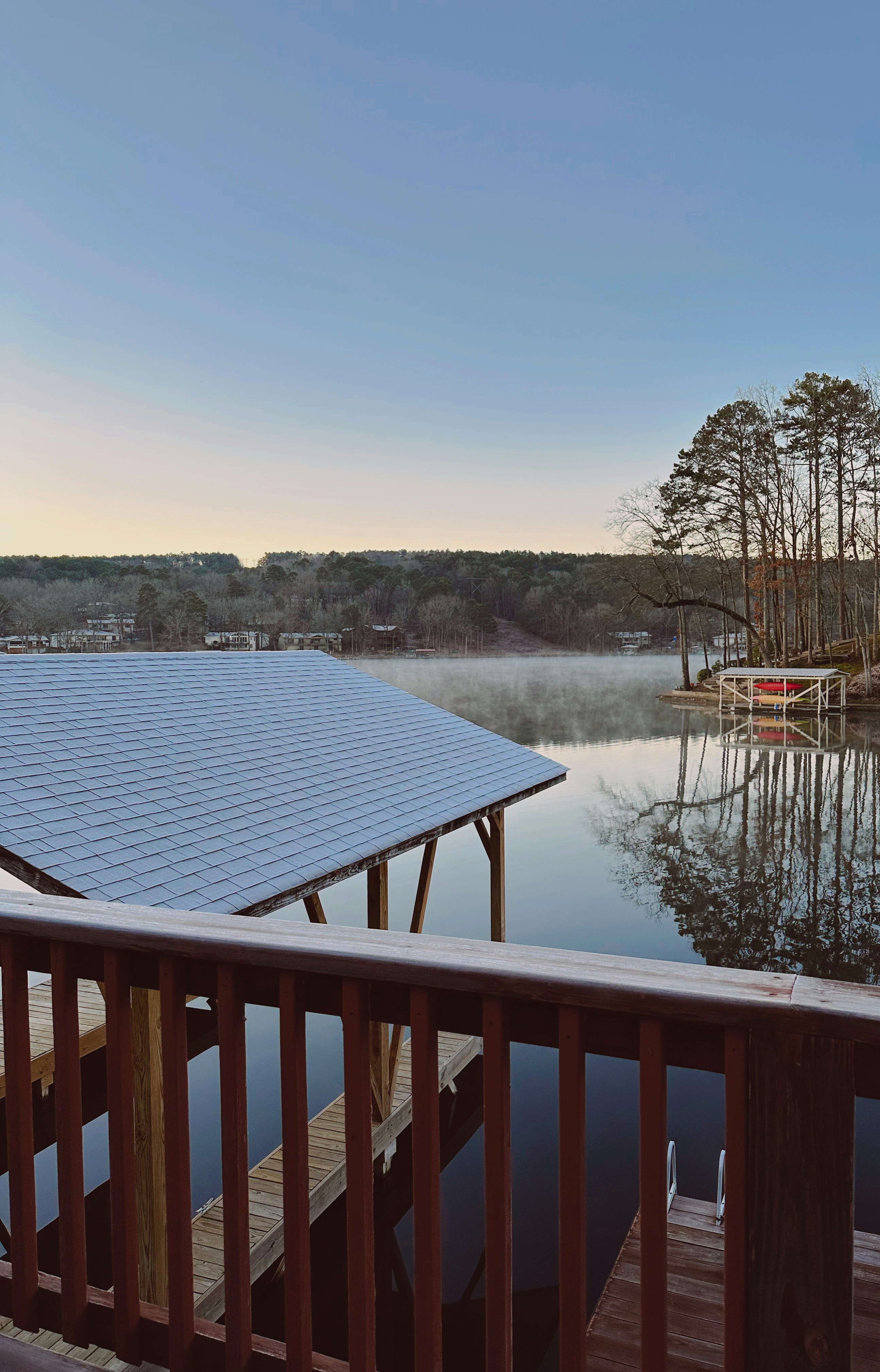 A dock with a dock house and a lake in the background