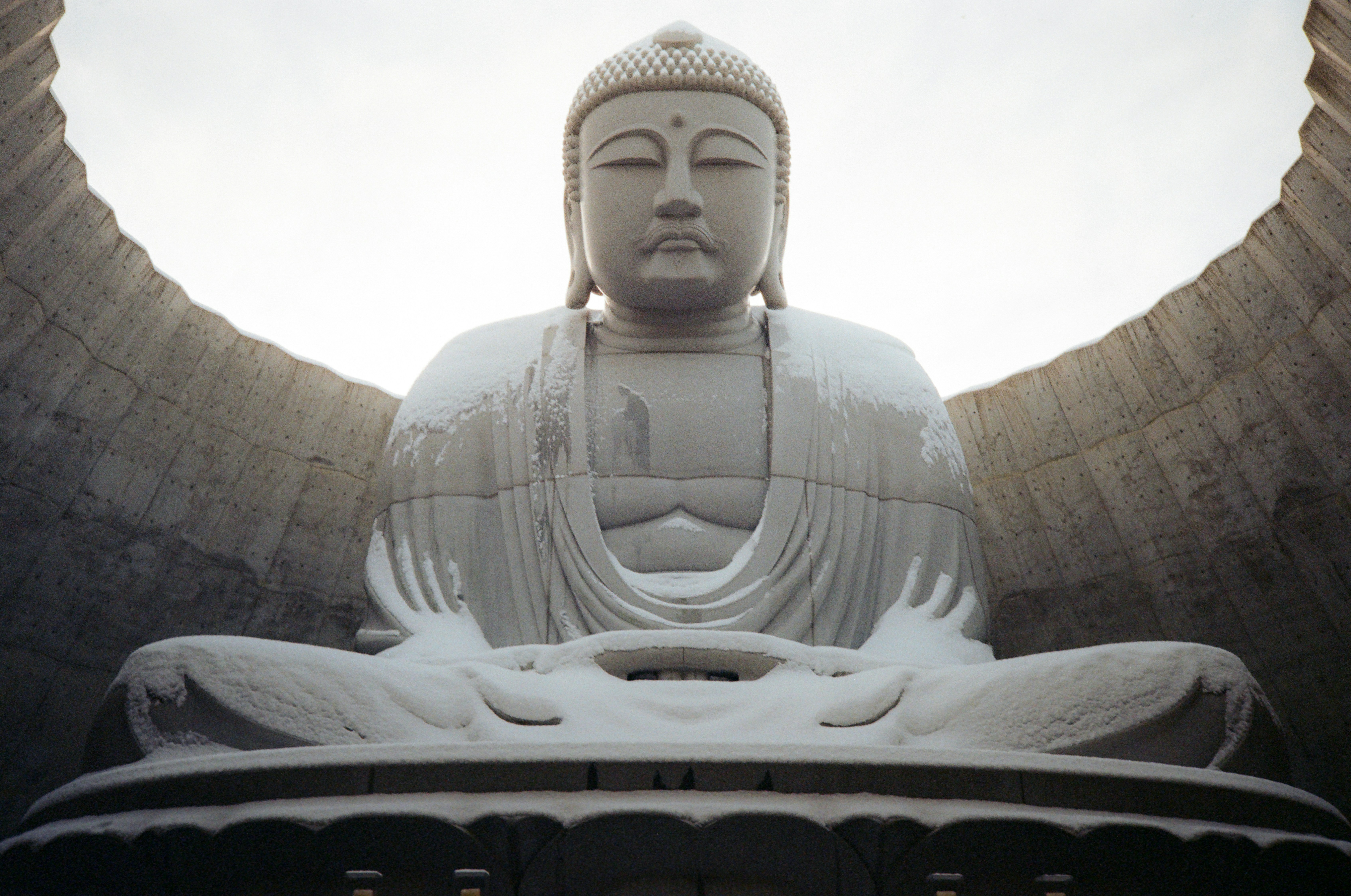 Une statue d’un bouddha assis devant un mur