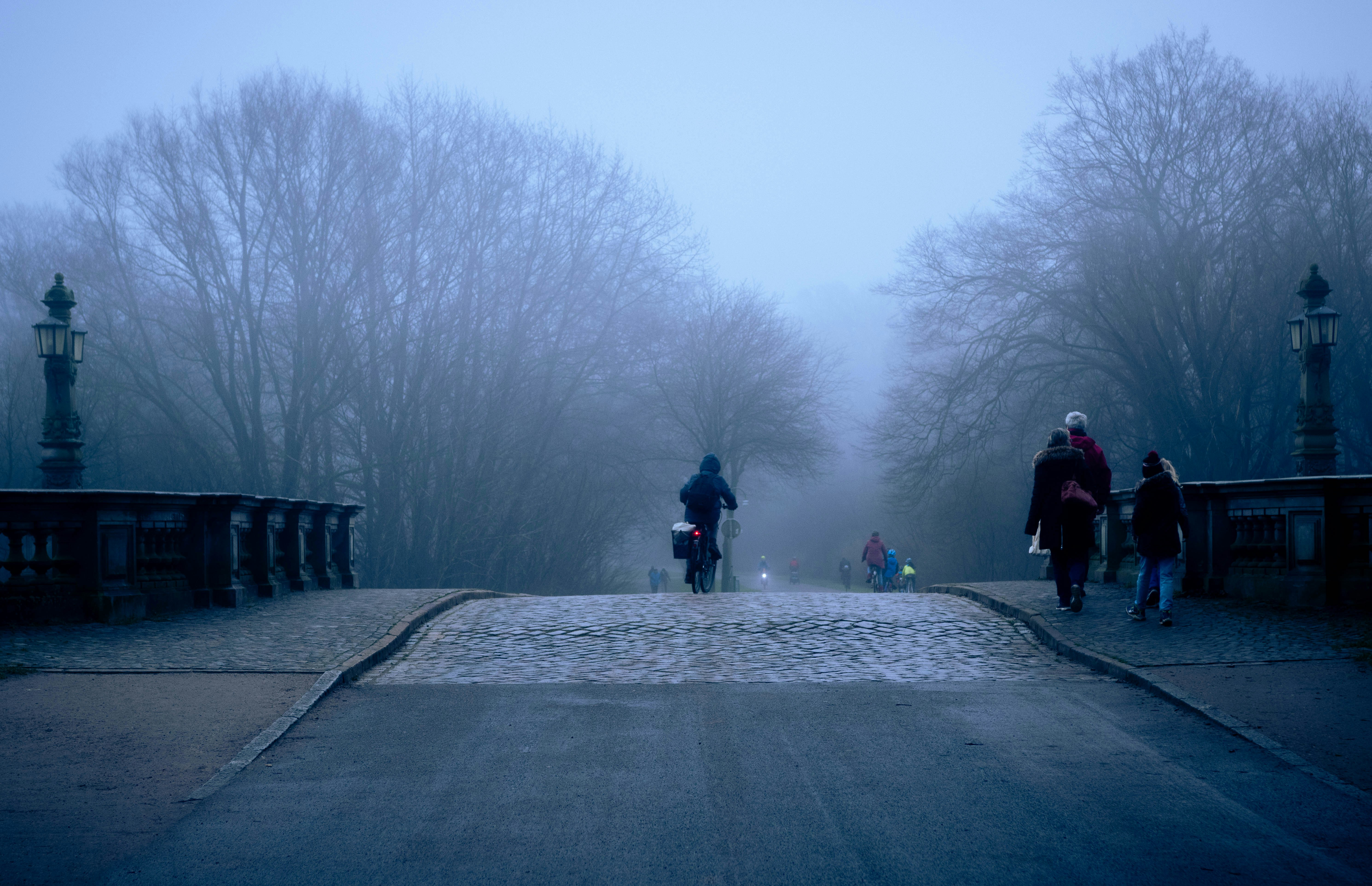 A group of people walking across a bridge on a foggy day