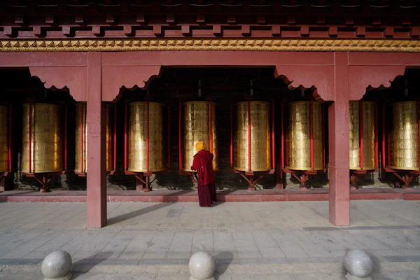 A person in traditional red robes in front of a temple