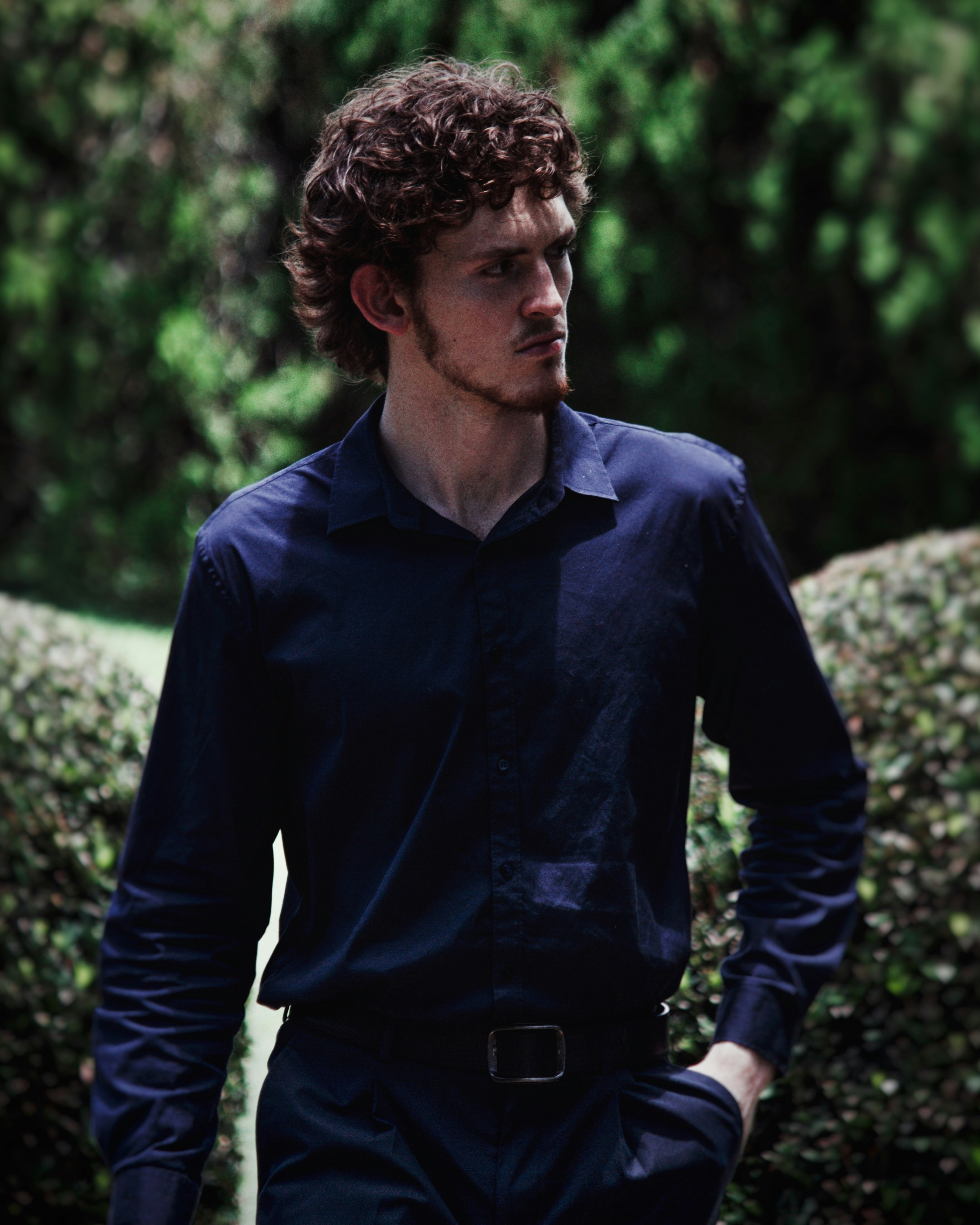 A man standing in front of a hedge