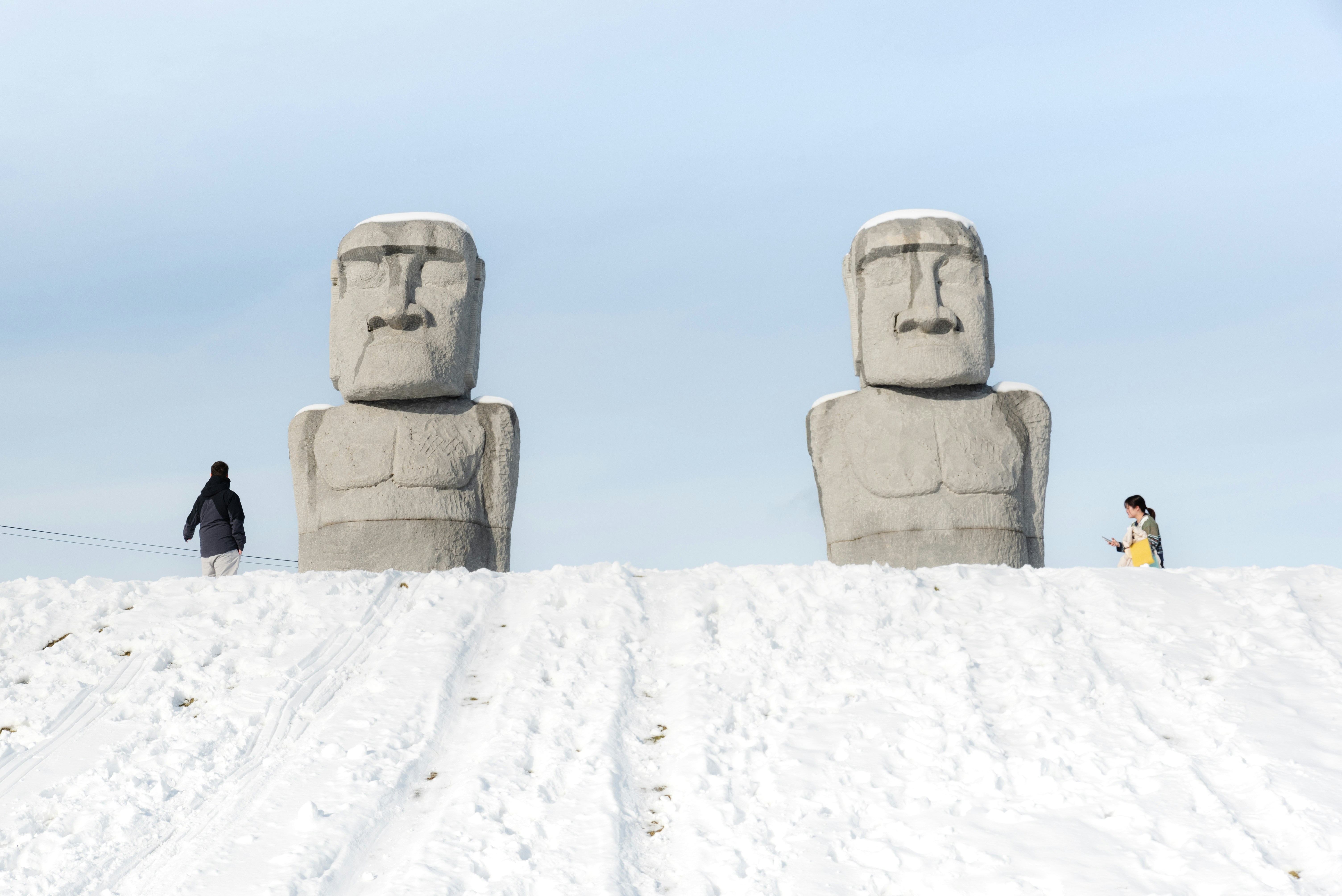 A group of people standing in the snow next to two totems