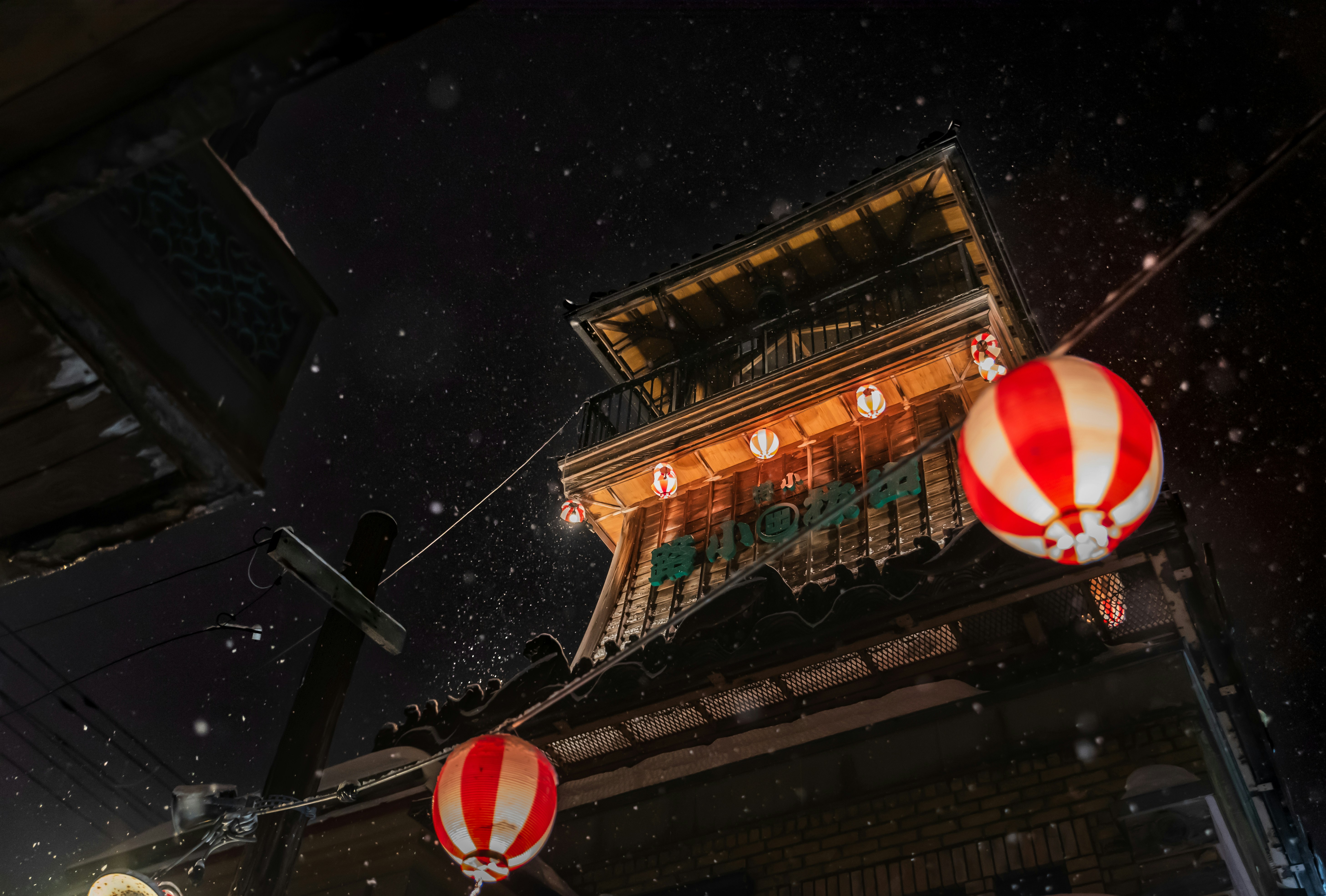 Two red and white lanterns hanging from the side of a building