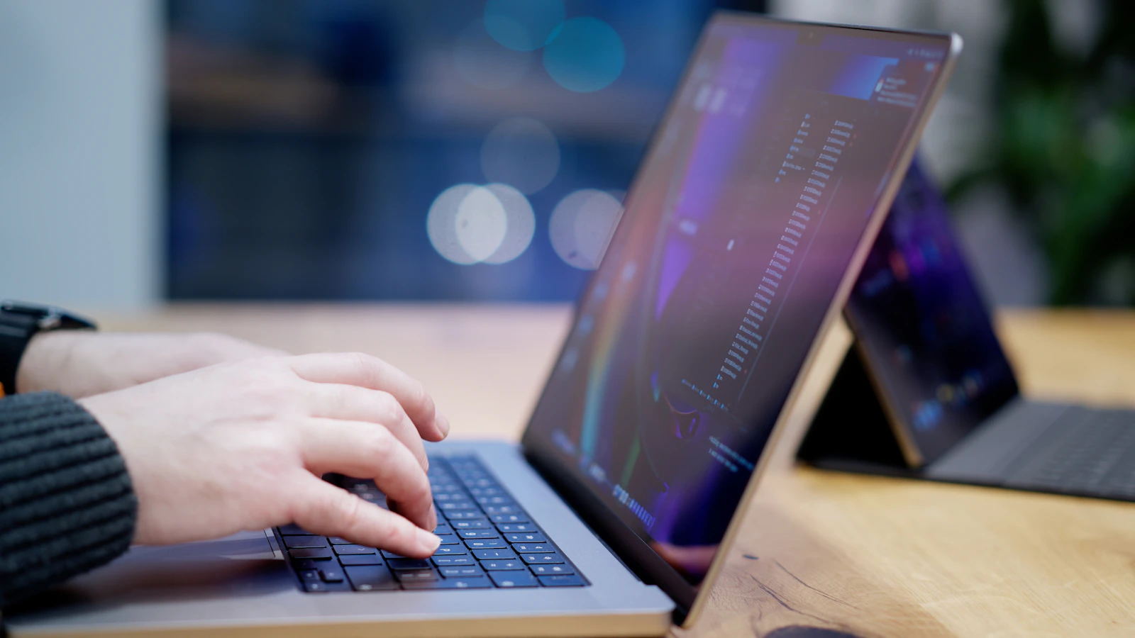 A person typing on a laptop keyboard on a desk