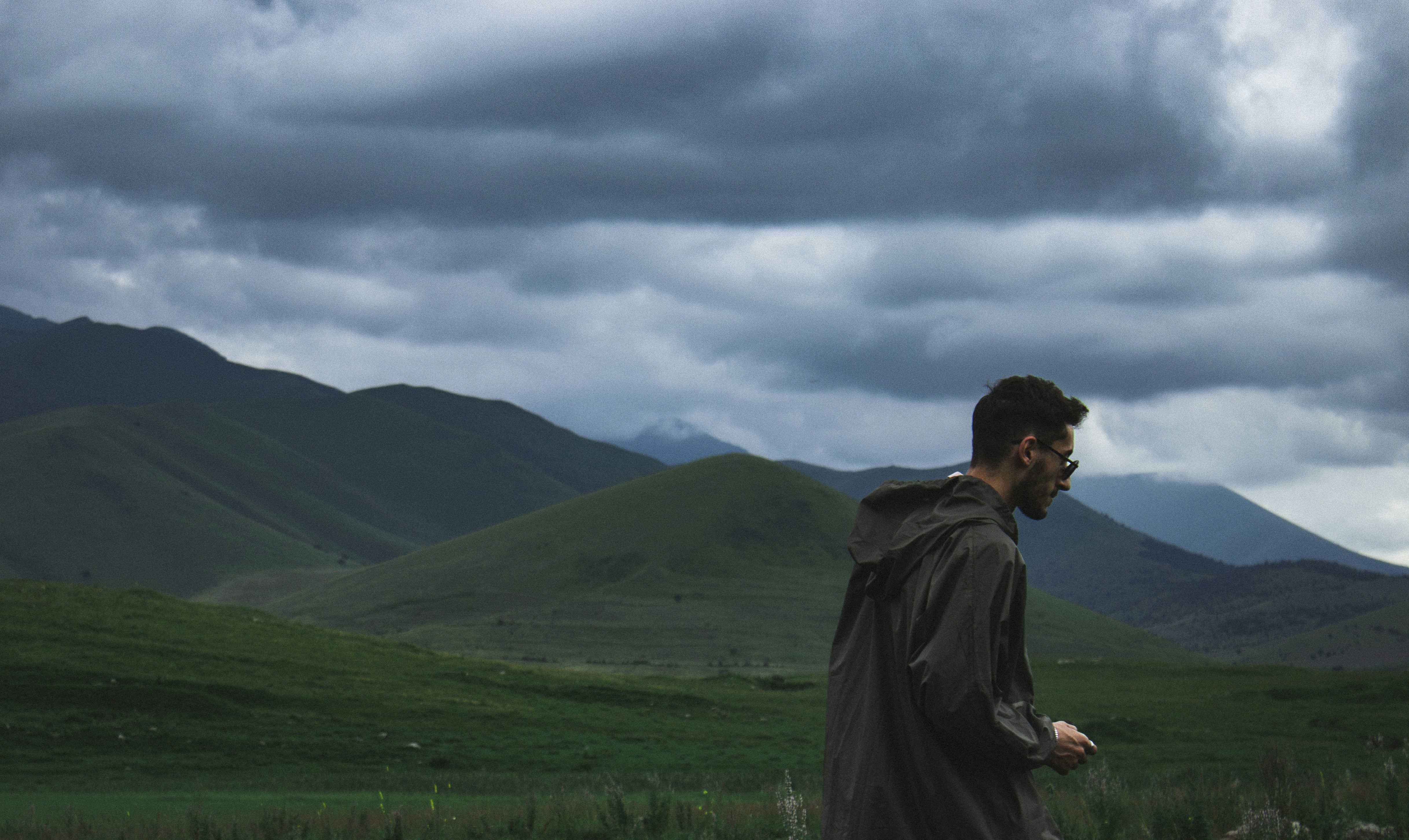 A man standing in a field with mountains in the background