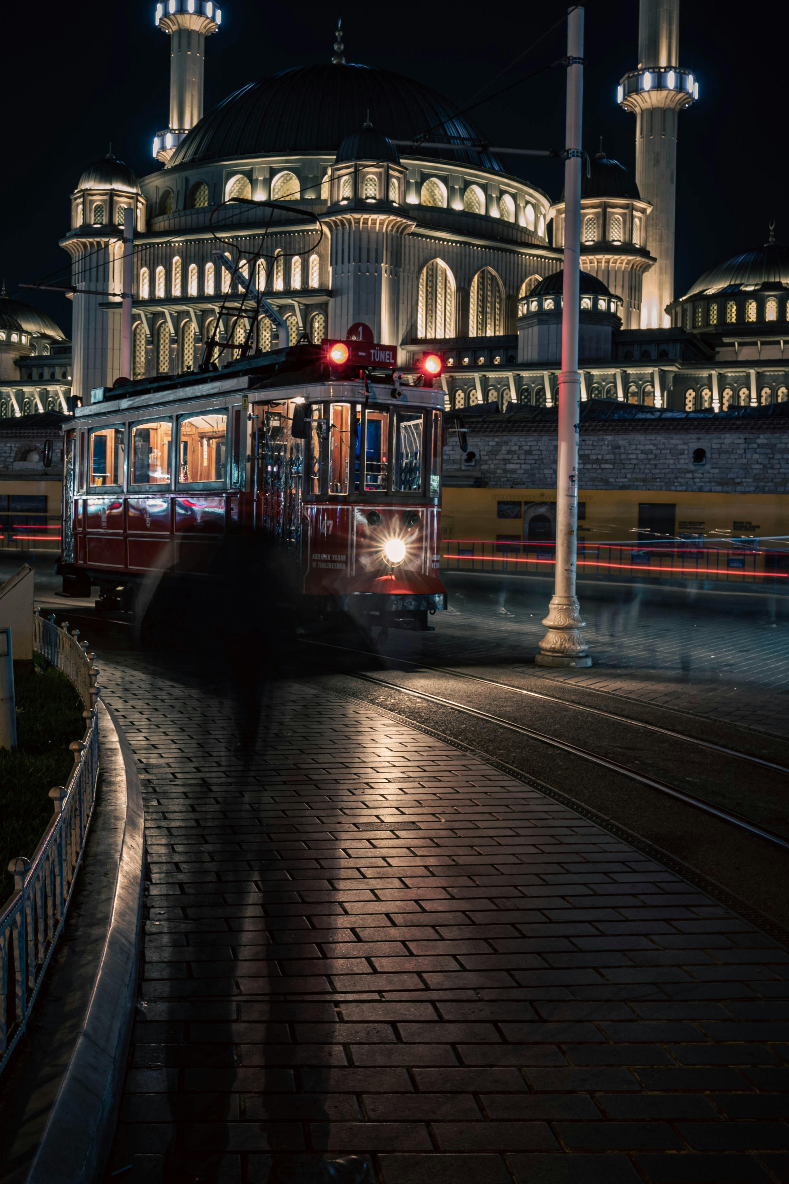 A red trolley driving down a street next to a tall building