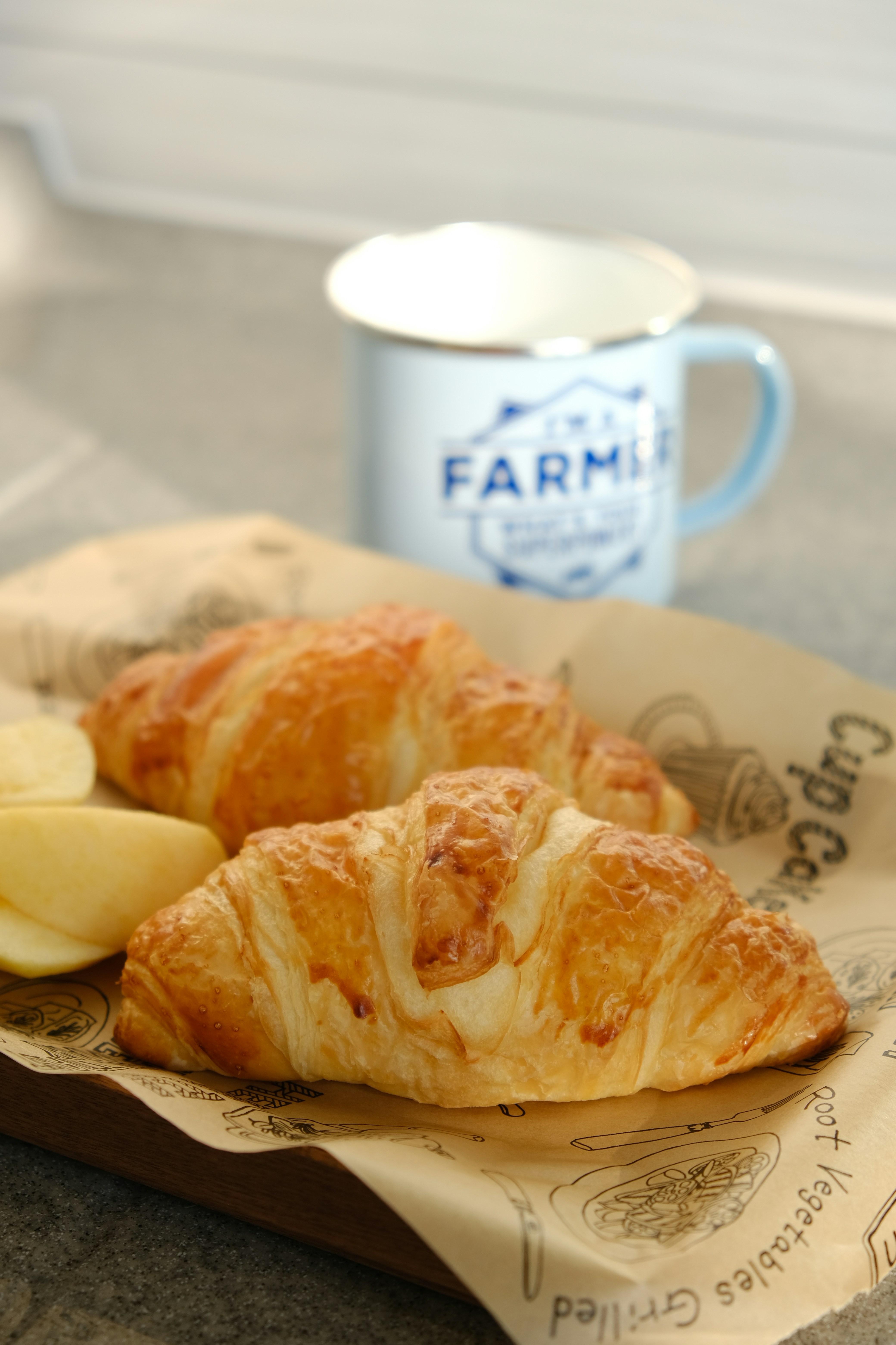 A croissant sitting on top of a piece of paper next to a cup