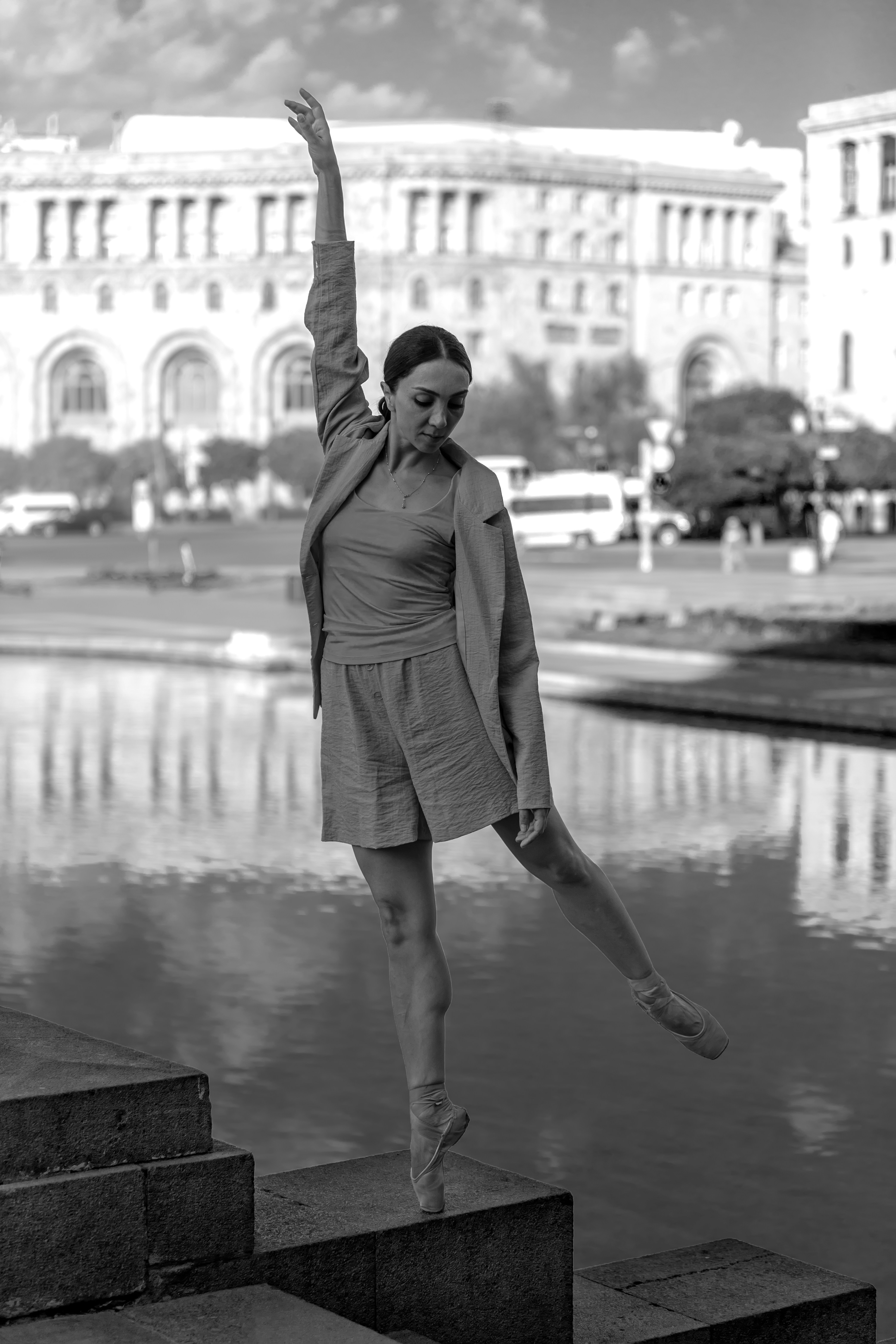A woman is standing on some steps in front of a body of water