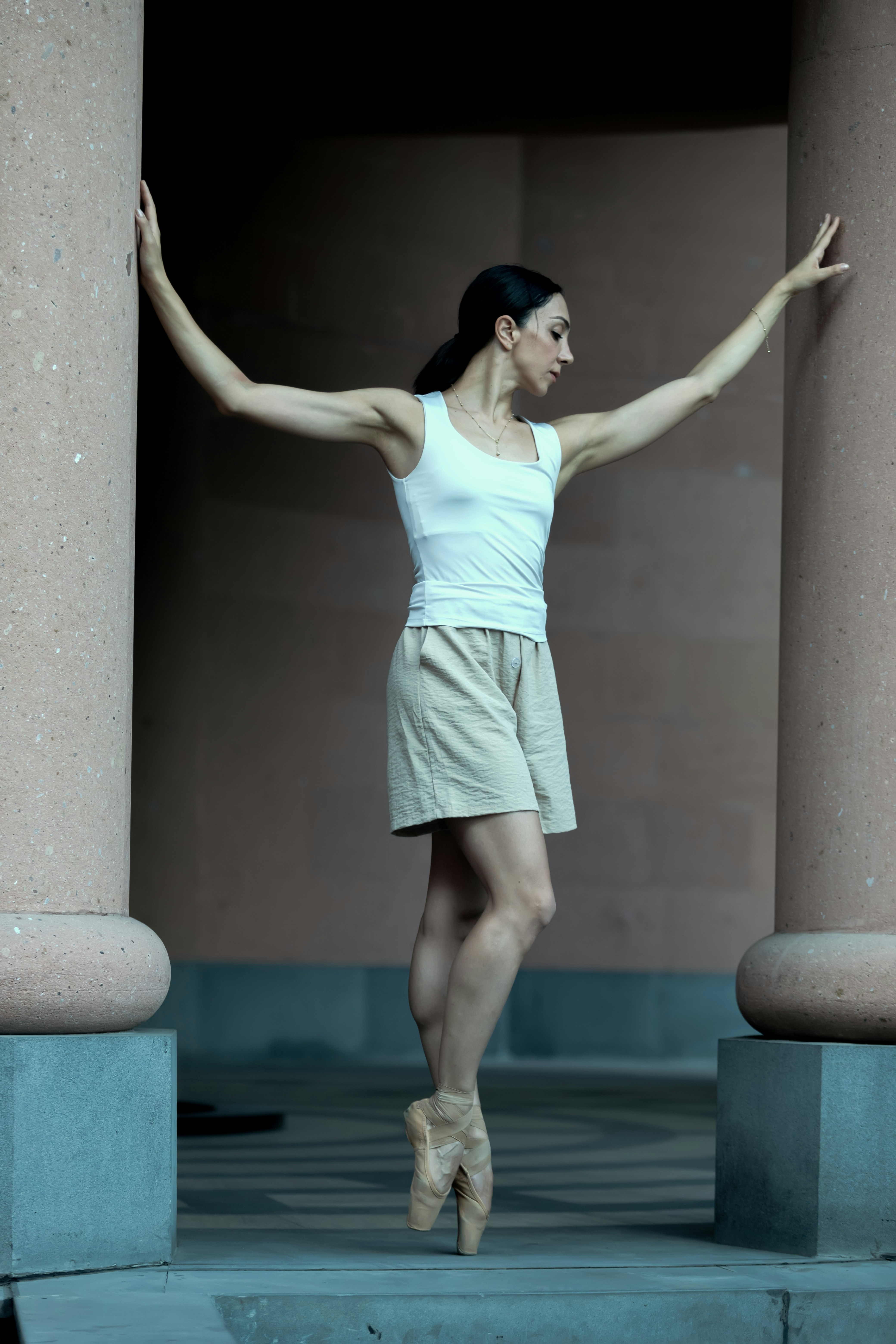 A woman in a white shirt and tan skirt standing in front of some pillars