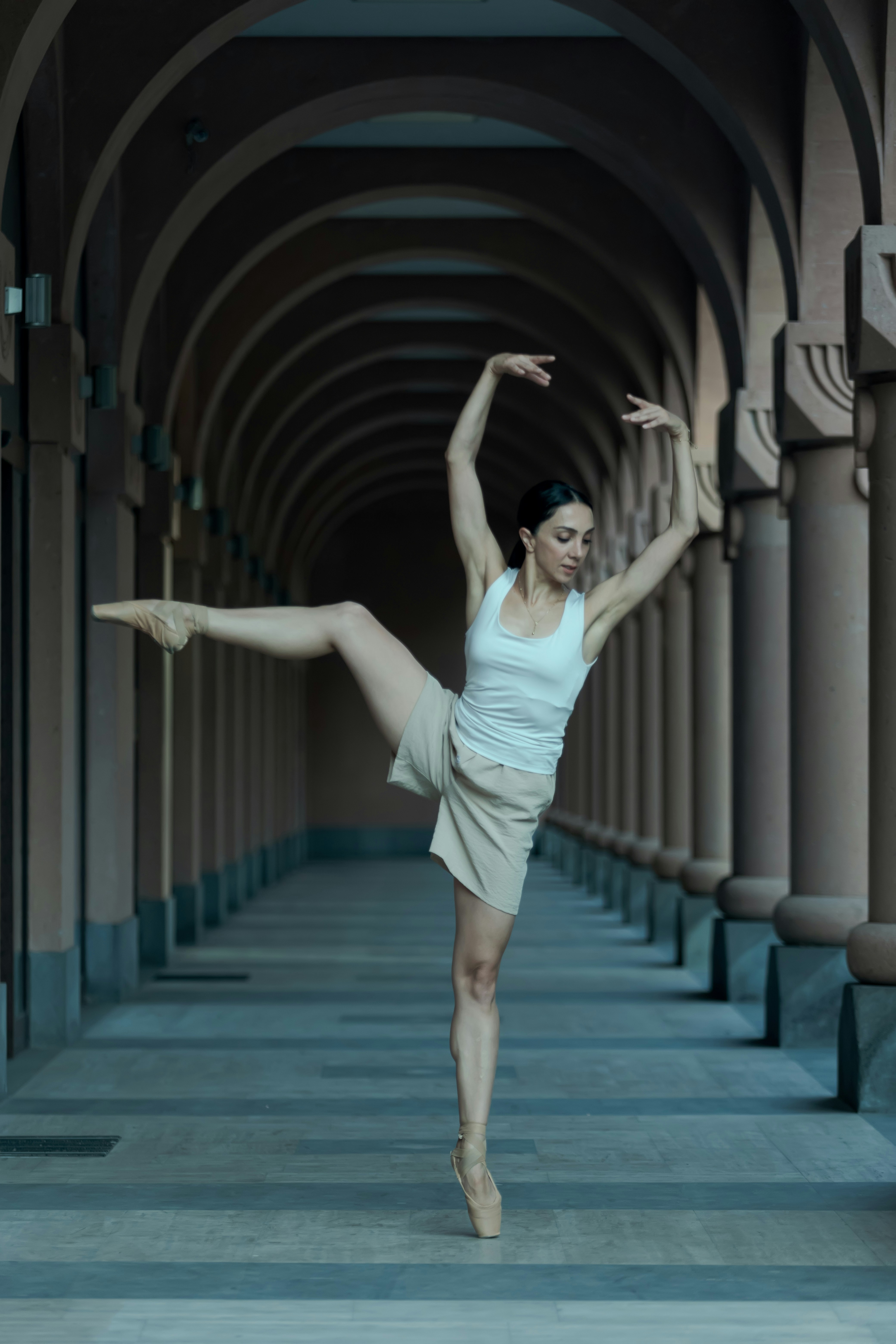 A woman in a white top is doing a ballet pose