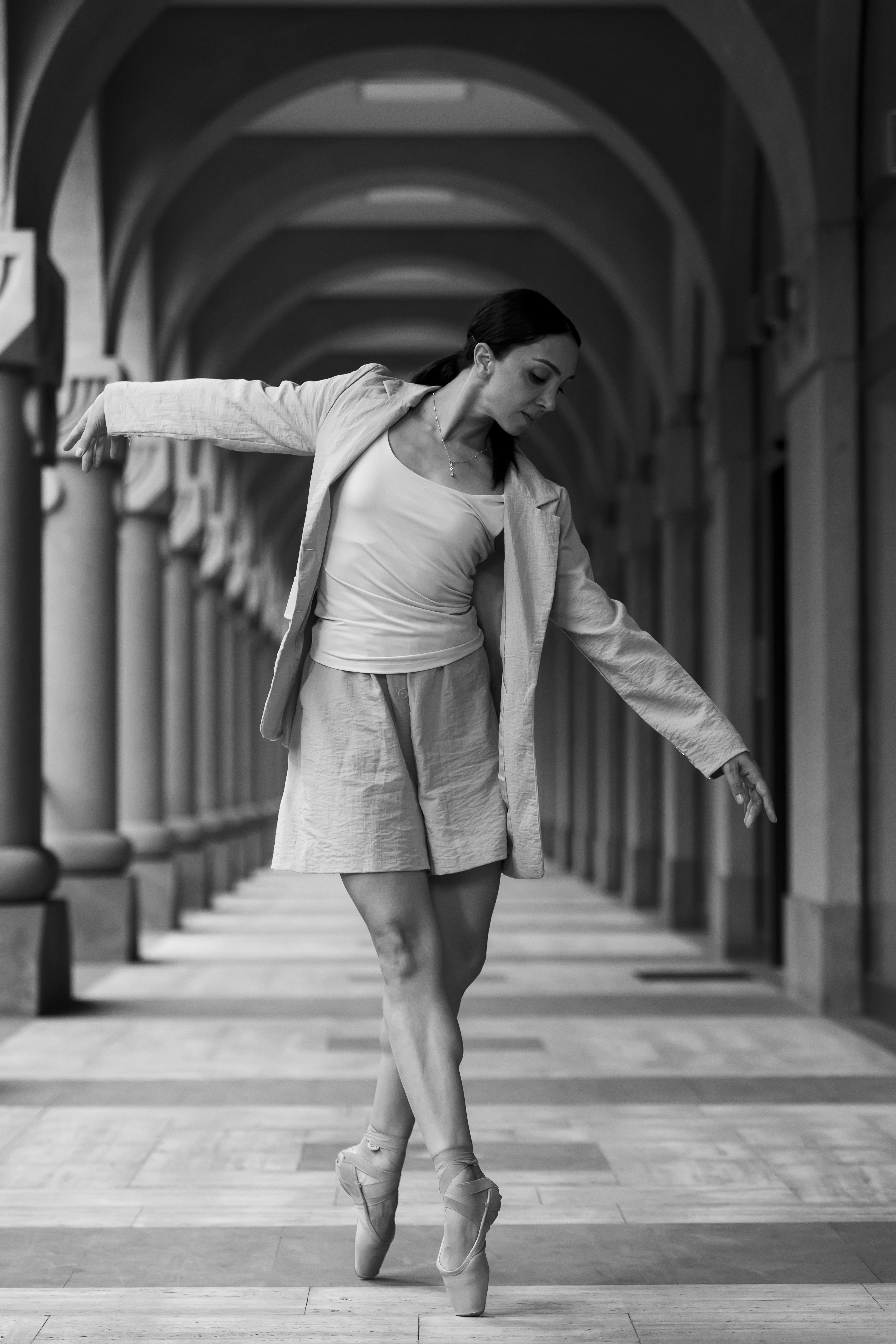 A woman walking down a hallway next to columns