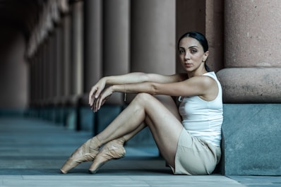 A woman sitting on the ground in front of a building