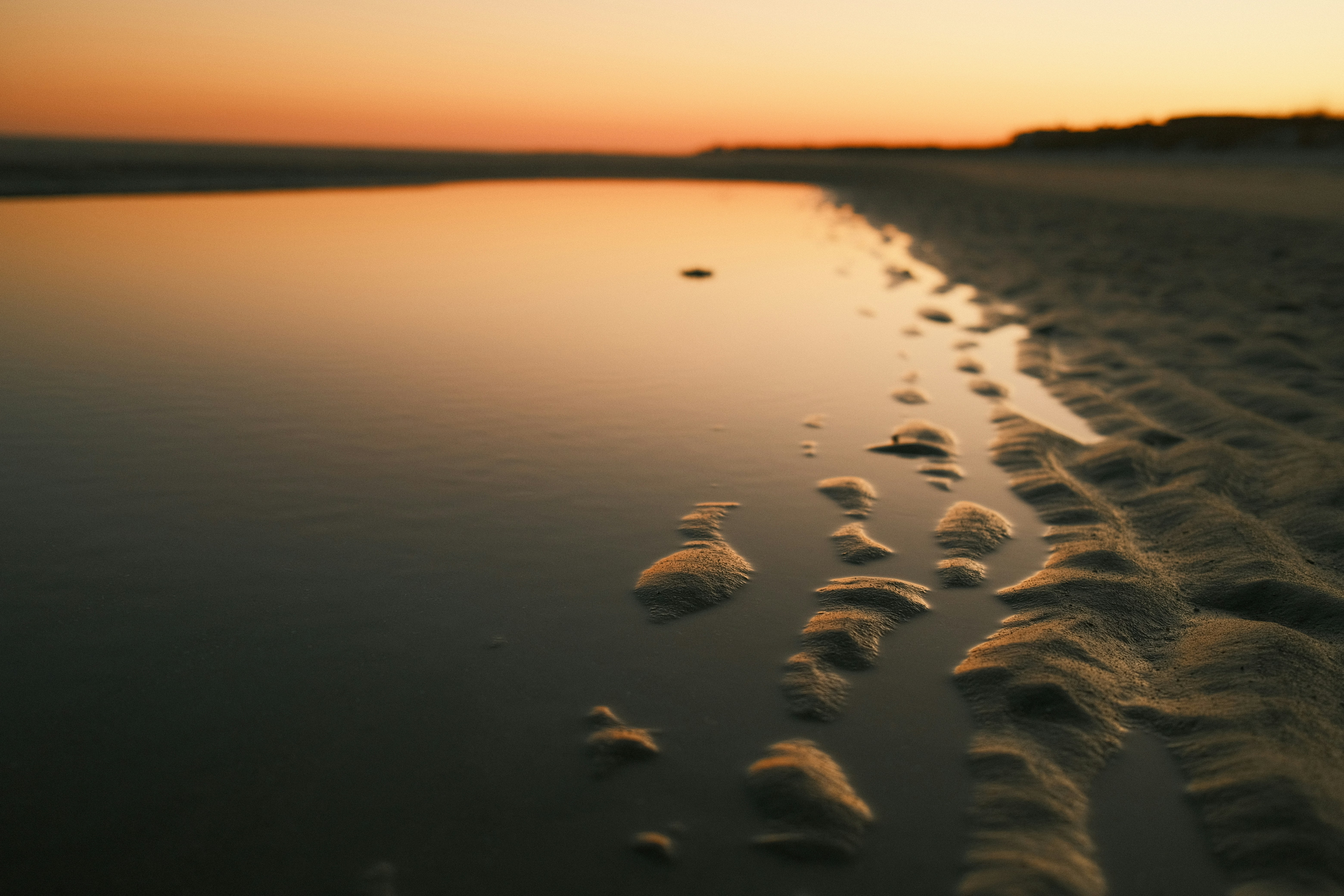 Footprints in the sand on a beach at sunset