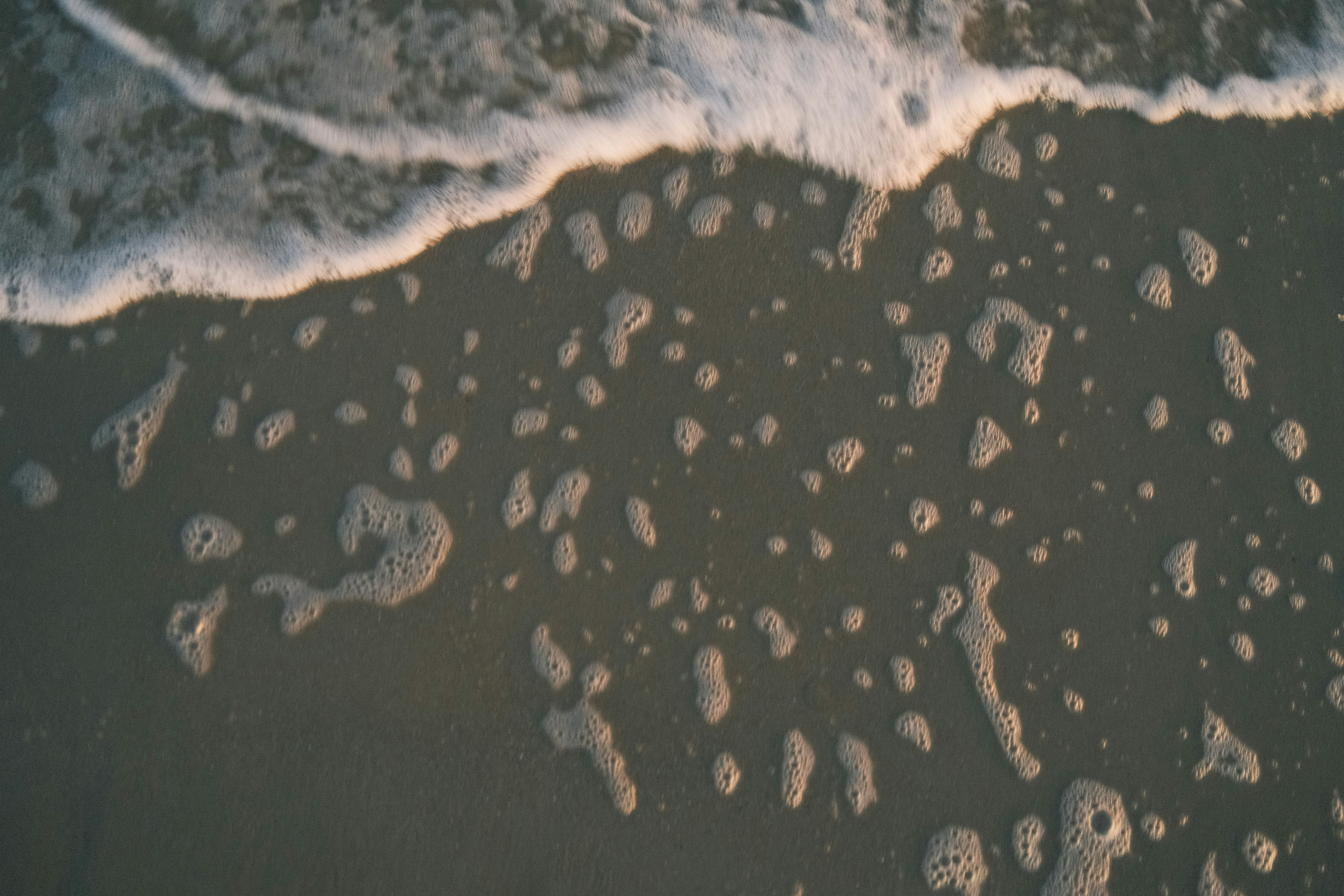 An aerial view of a beach with a wave coming in