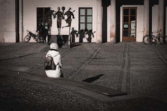 A person sitting on the ground in front of a building