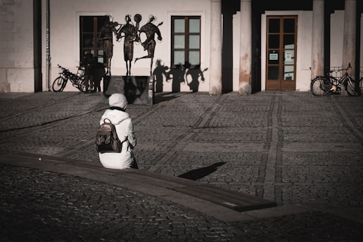 A person sitting on the ground in front of a building