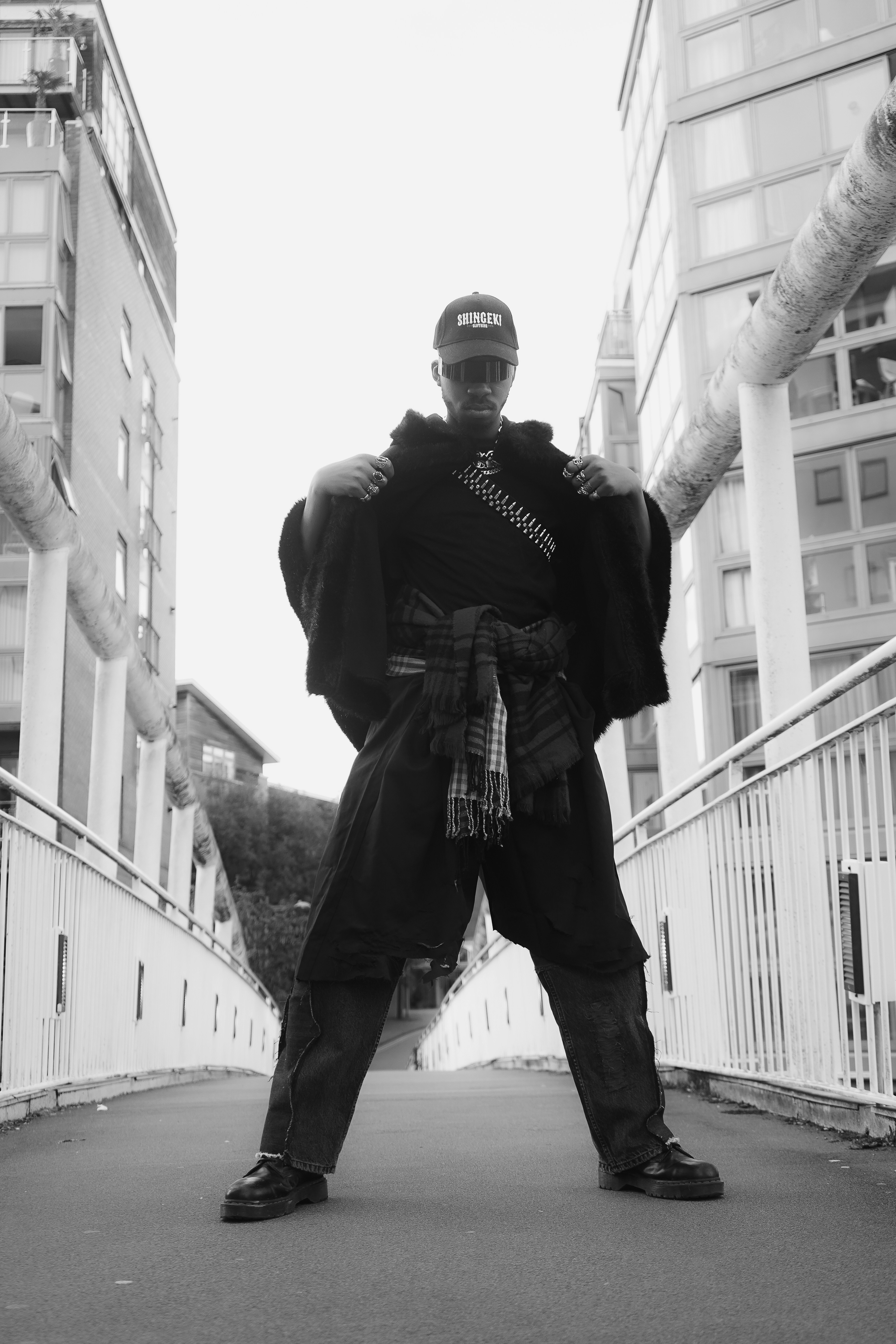 A man standing on a bridge in a black and white photo